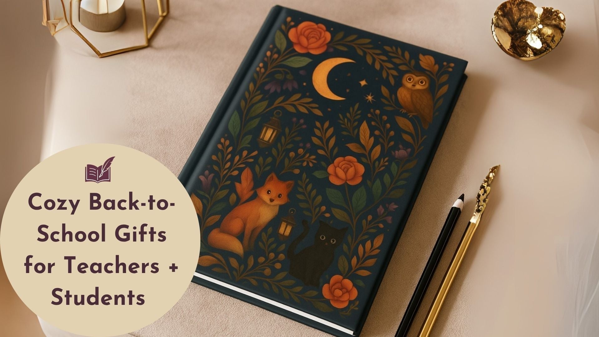 Illustrated journal with fox, cat, and floral design on cover, placed in a cozy flatlay with gold accessories and pencils.