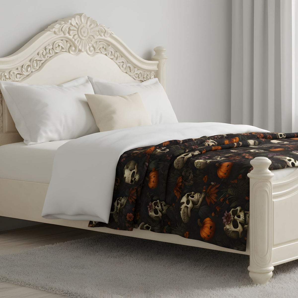 Dark floral Halloween throw blanket spread across a cream bed in a light neutral room.