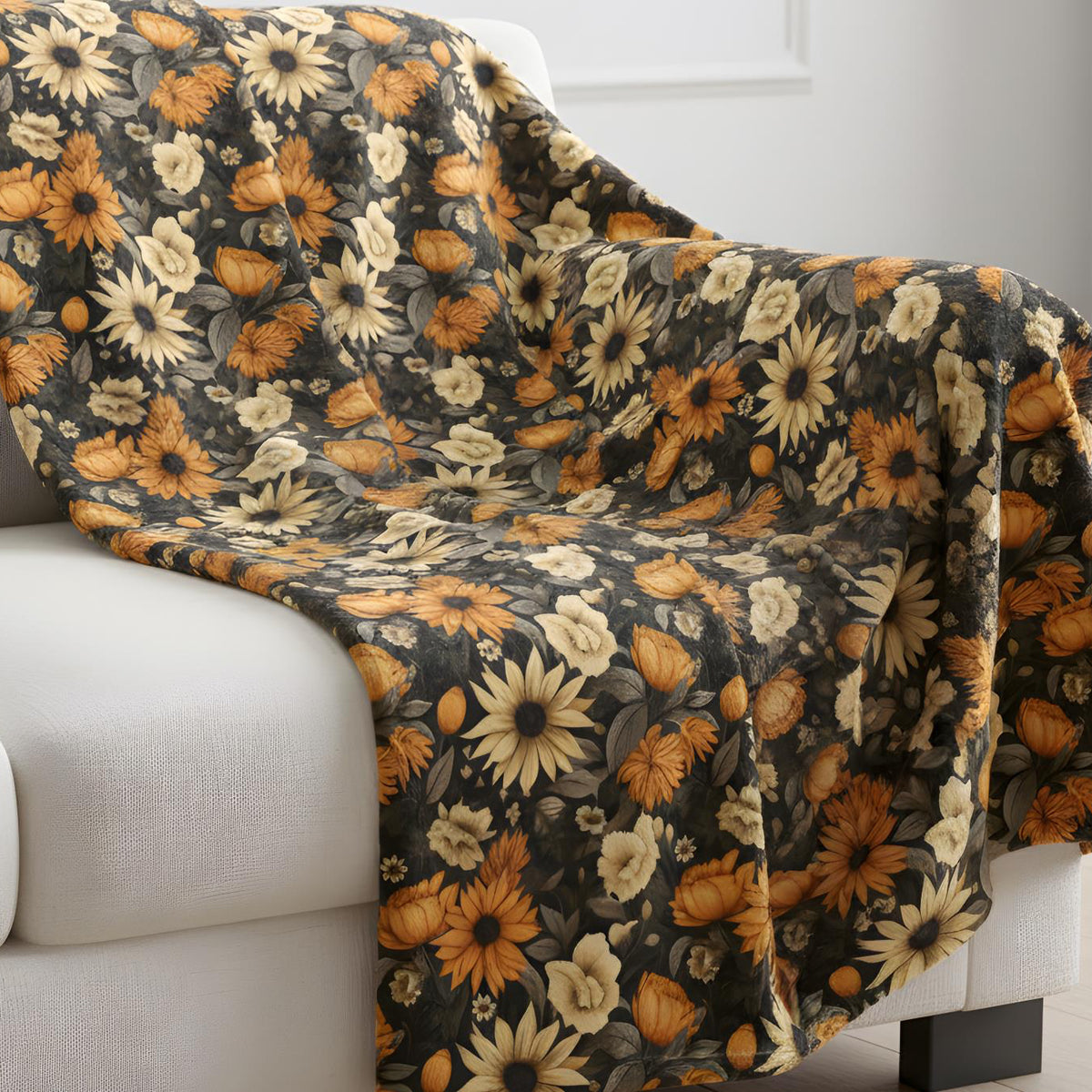 Floral-patterned blanket draped over a white sofa in a room with light-colored walls.