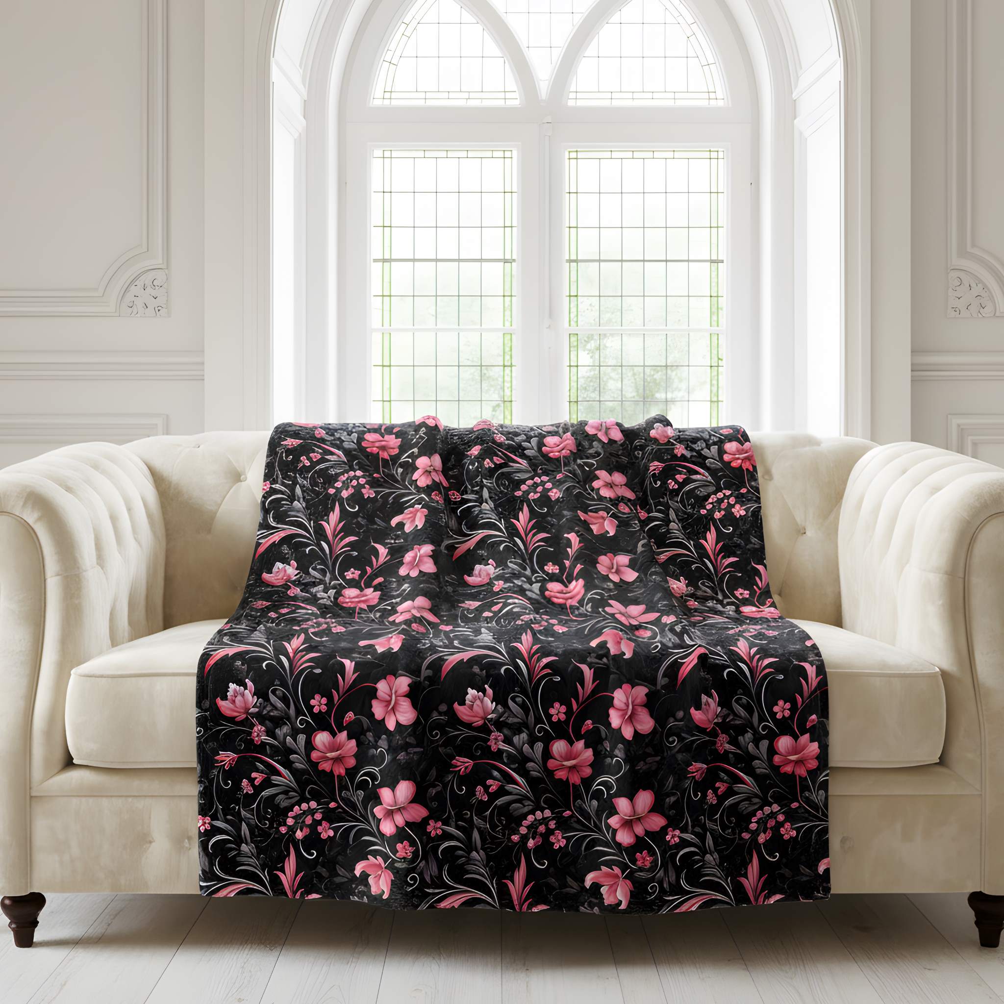 A pink and black dark floral throw blanket on a white sofa in a gothic living room.