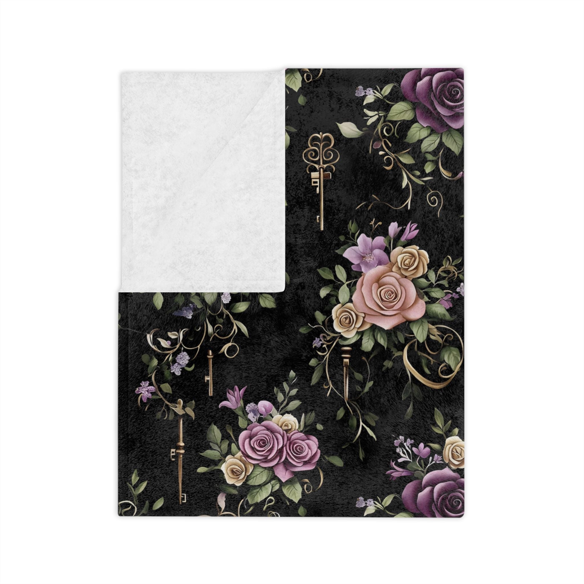 Folded dark floral blanket close-up with antique key and Victorian botanical print with white backside.