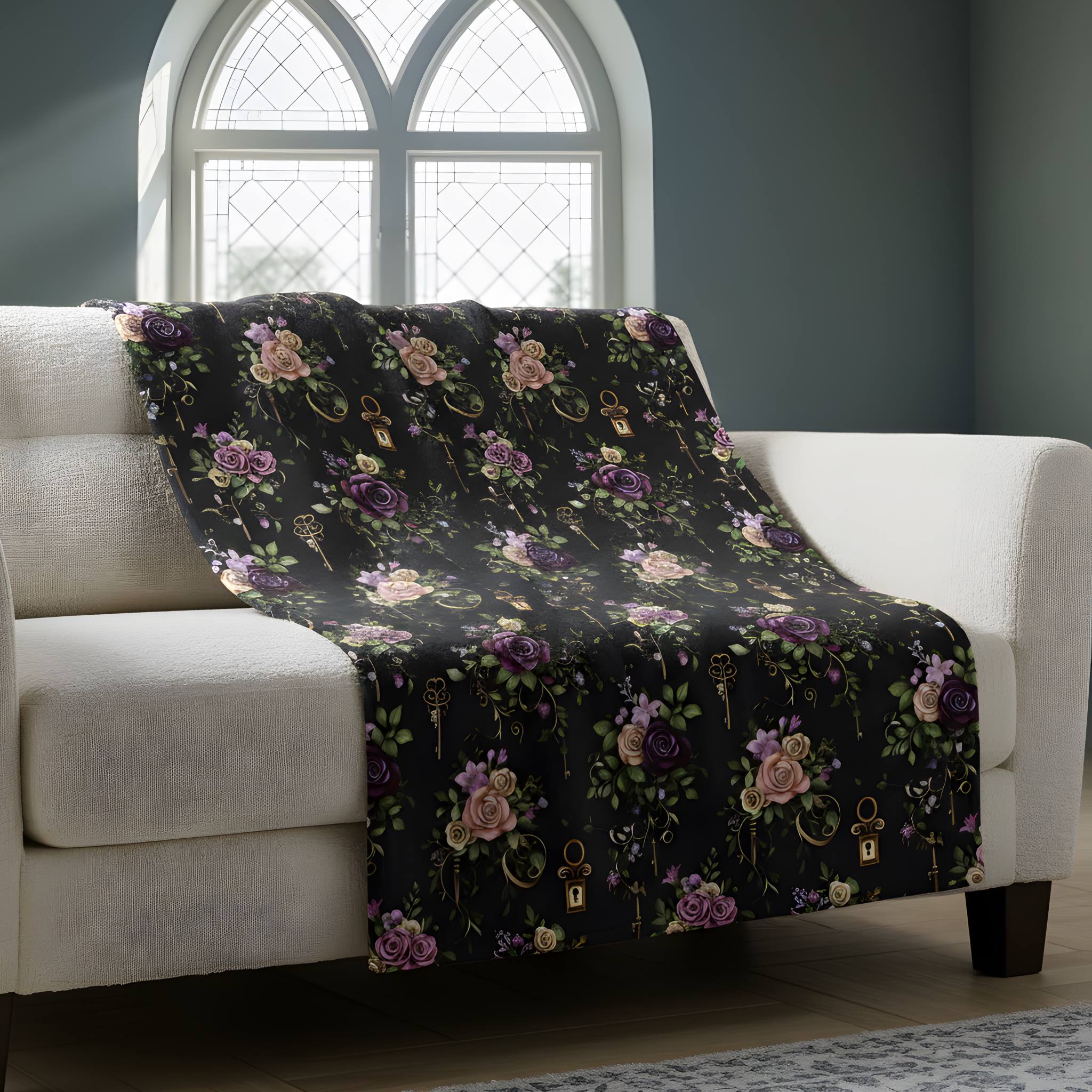 Victorian Gothic throw blanket with antique keys and dark florals draped across a white couch