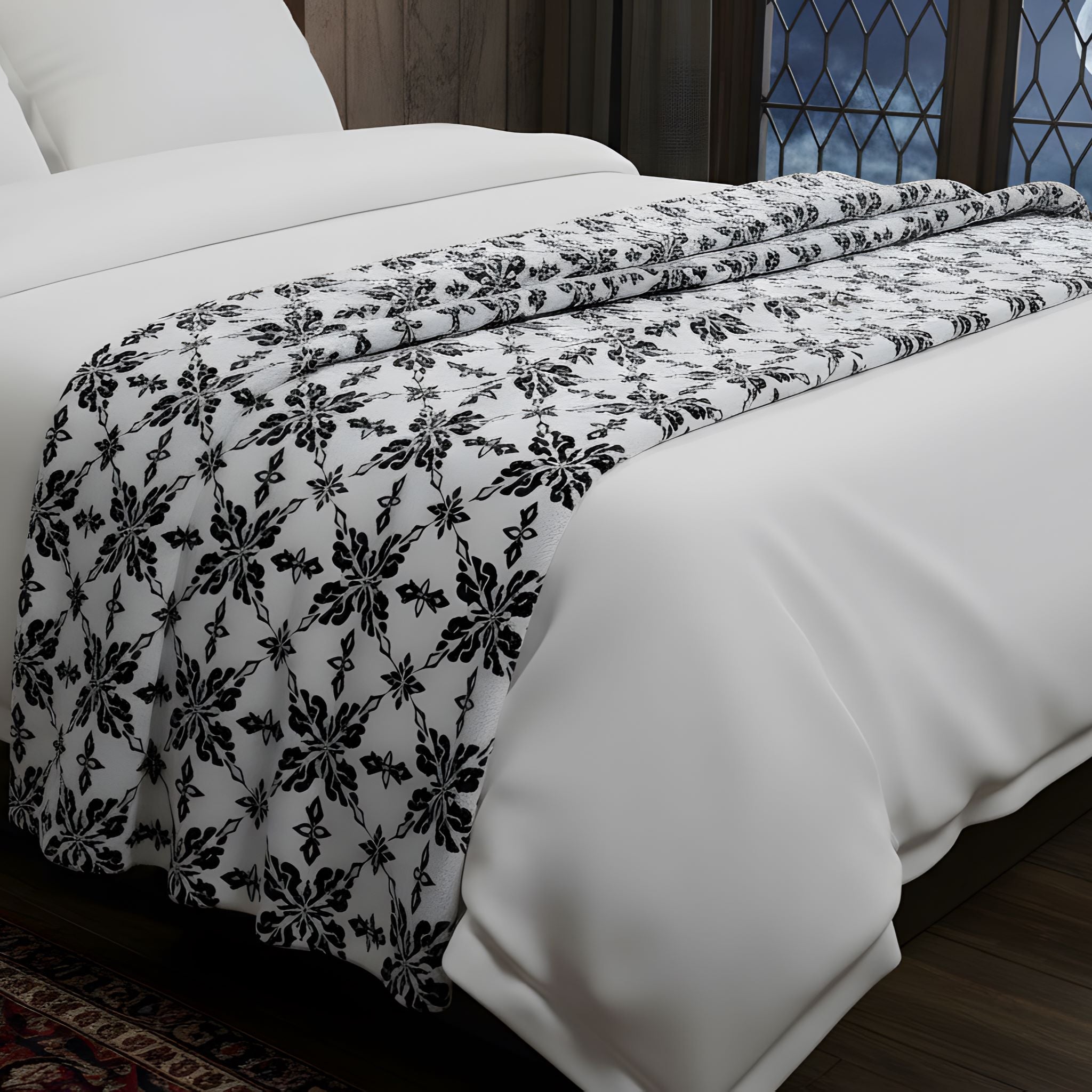 White bed with a black and white damask velveteen throw.