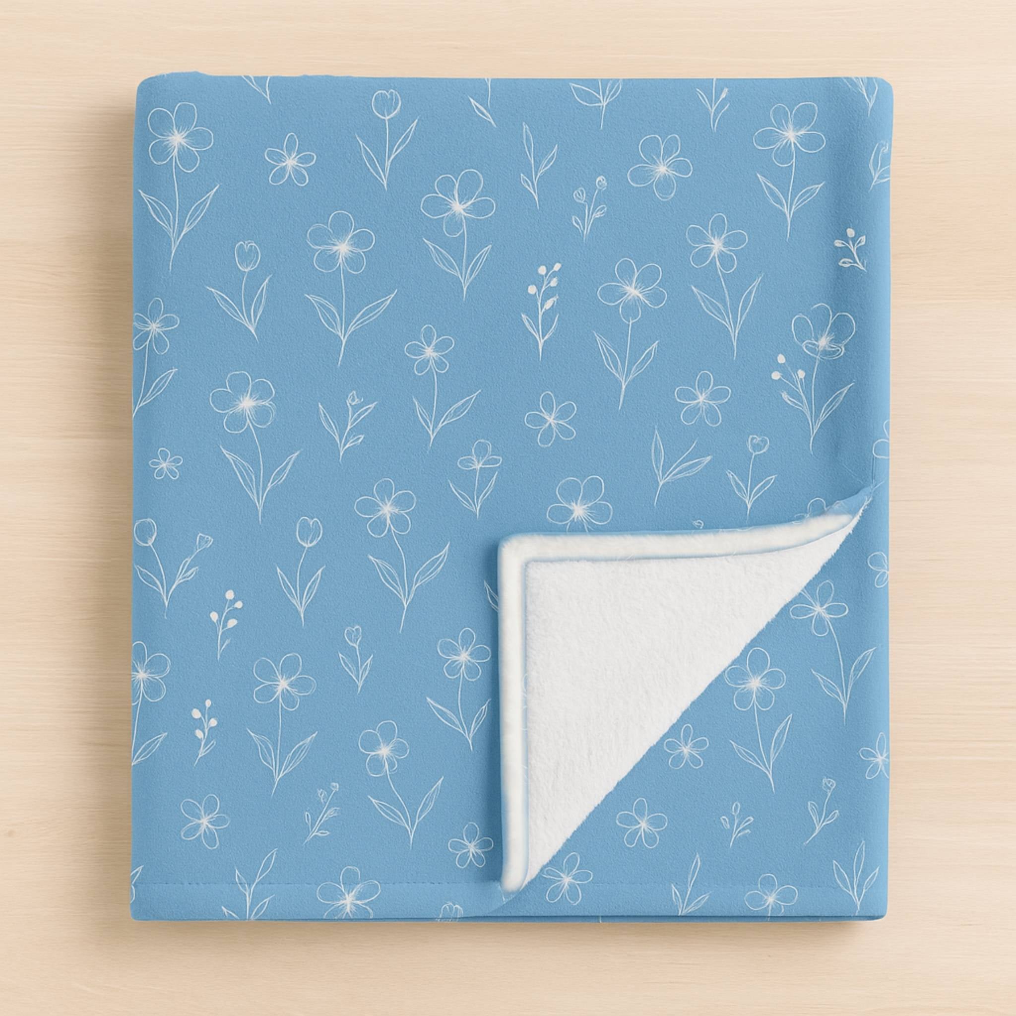 Blue floral throw blanket with a Minky white floral pattern on a beige background