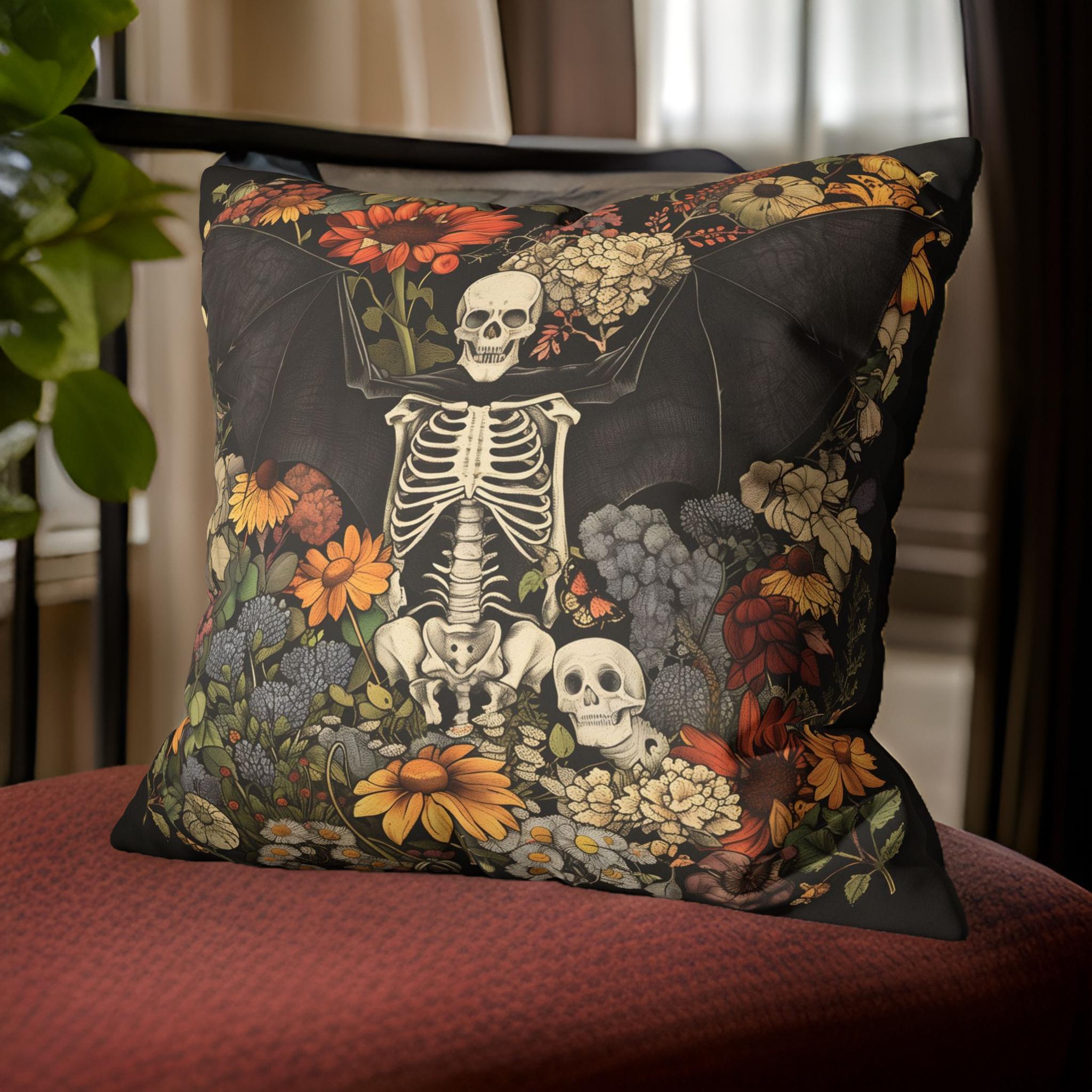 A decorative throw pillow with a vintage illustration of a bat skeleton surrounded by floral gothic designs, displayed on a chair.
