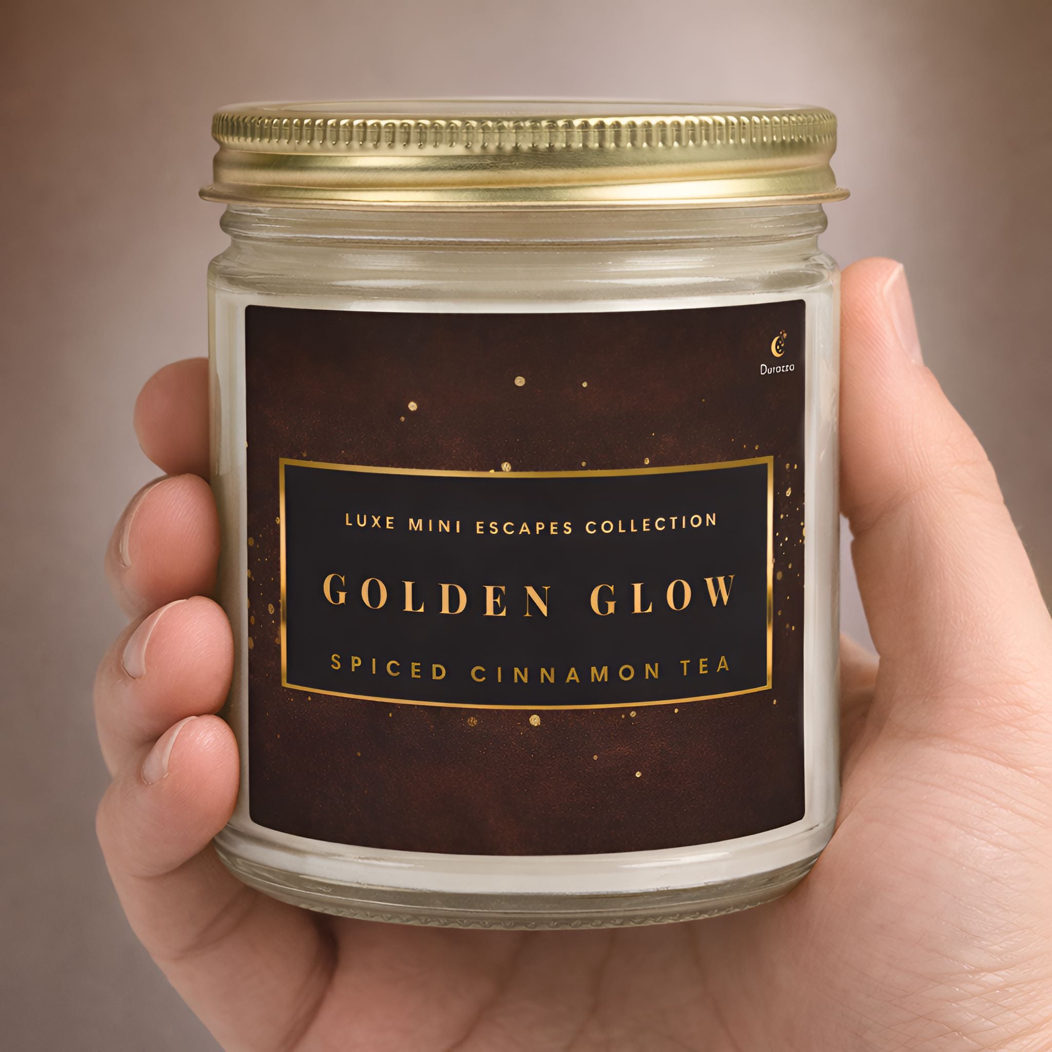 Spiced cinnamon tea scented candle in a 9 oz clear jar with a gold lid sitting in a persons hand to show accurate size.