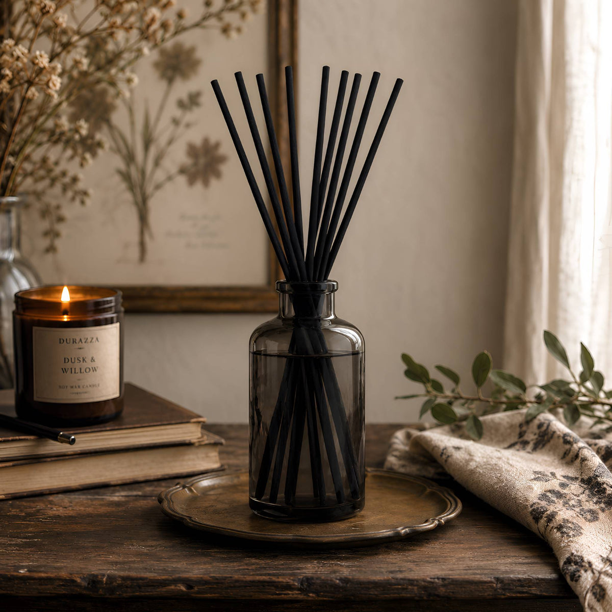 Diffuser reeds collection with black reed diffuser, candle, botanical art, greenery, and warm cottage-gothic styling.