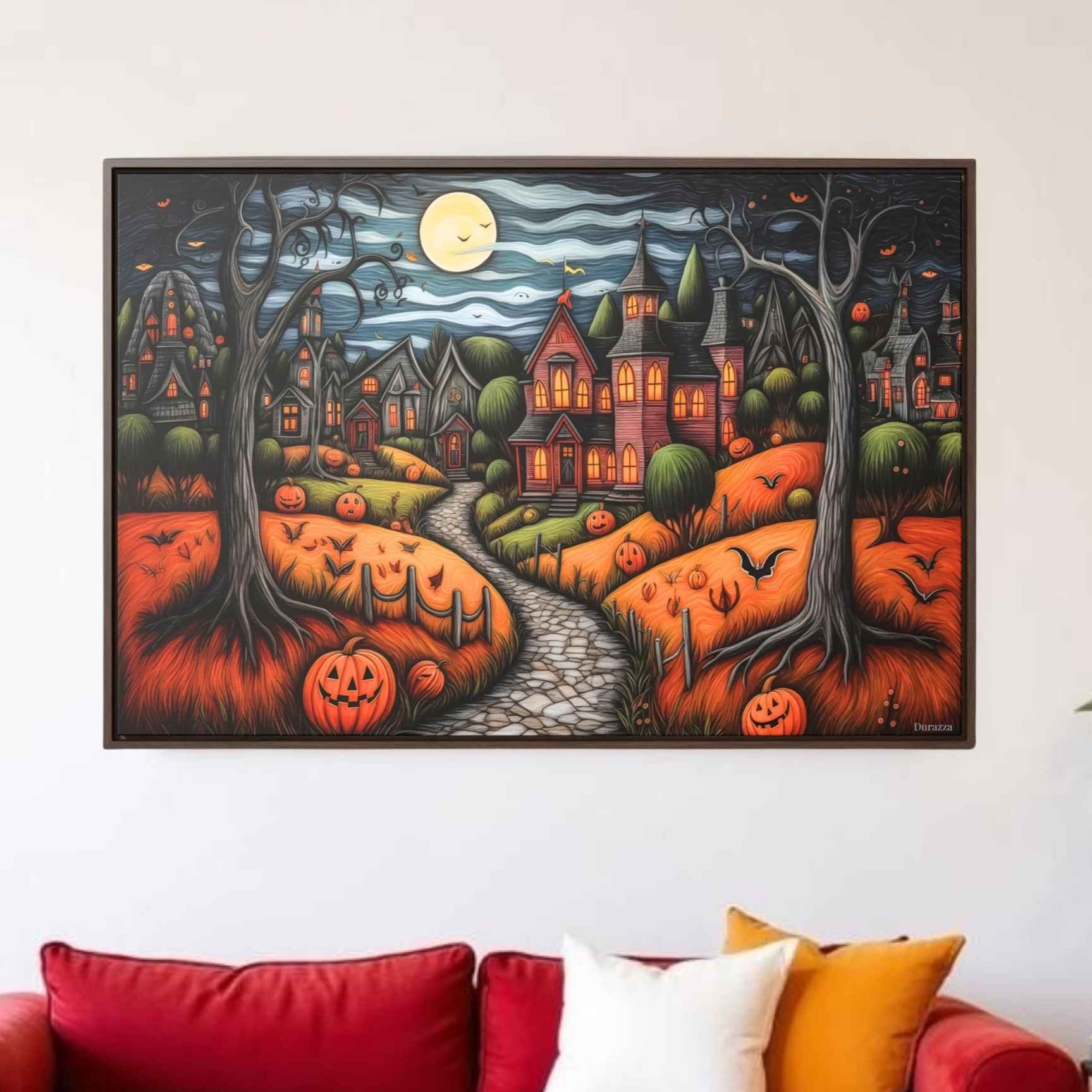 A canvas print featuring a vibrant and detailed illustration of a Halloween-themed village scene with a moonlit path, houses with pumpkins, and a autumnal color palette displayed above a red sofa in a living room setting.