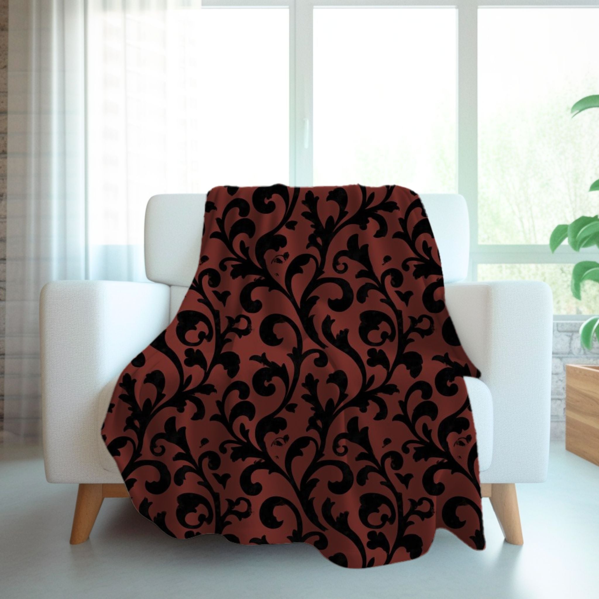 A dark red and black swirl throw blanket with a vintage design draped over a white chair in a cozy living room setting.