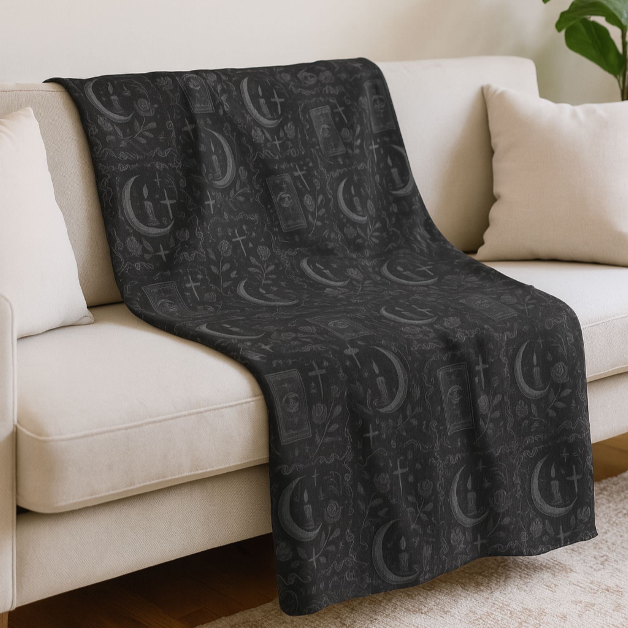 Black patterned throw blanket draped over a beige sofa.