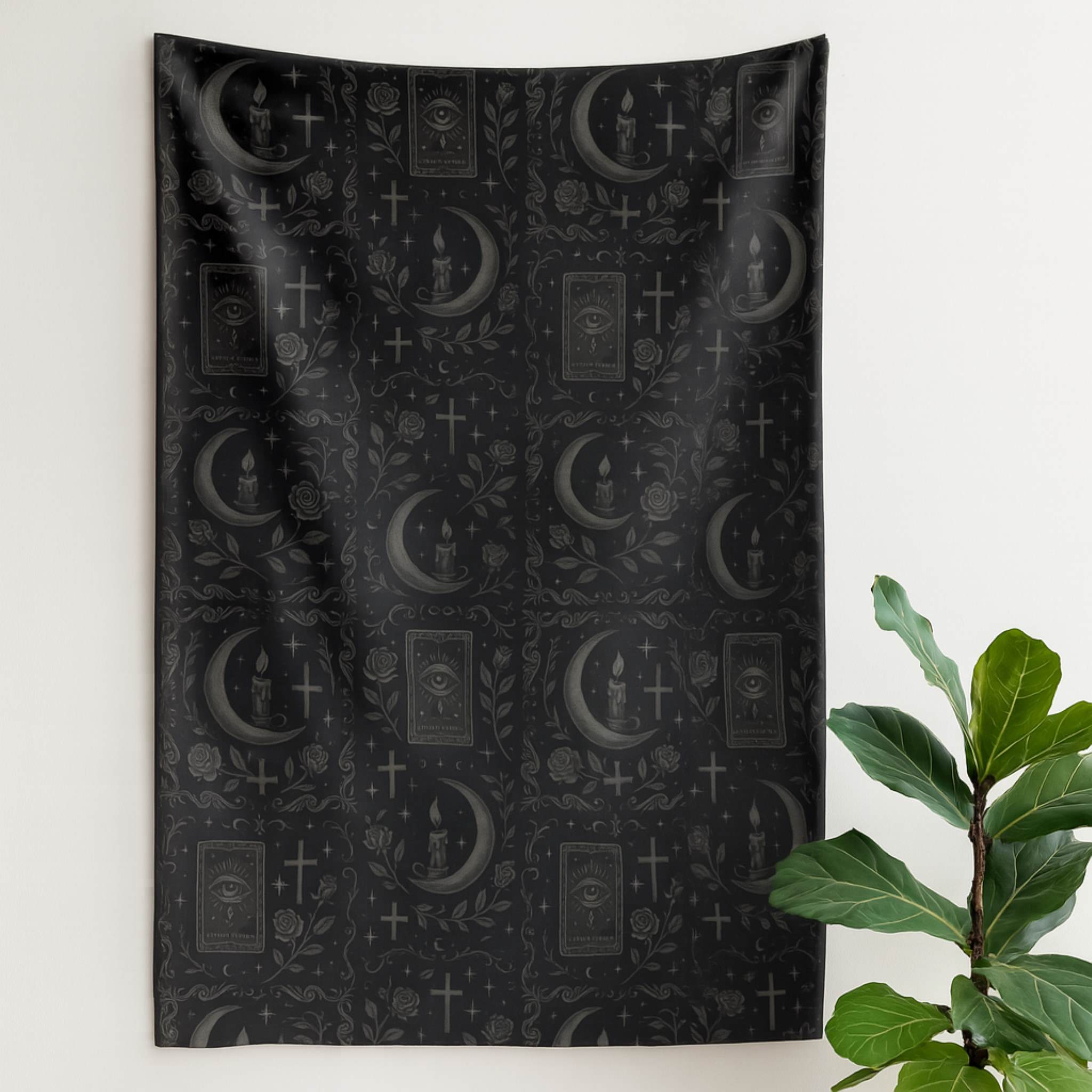 Black velveteen blanket with mystical symbols on a white wall next to a plant