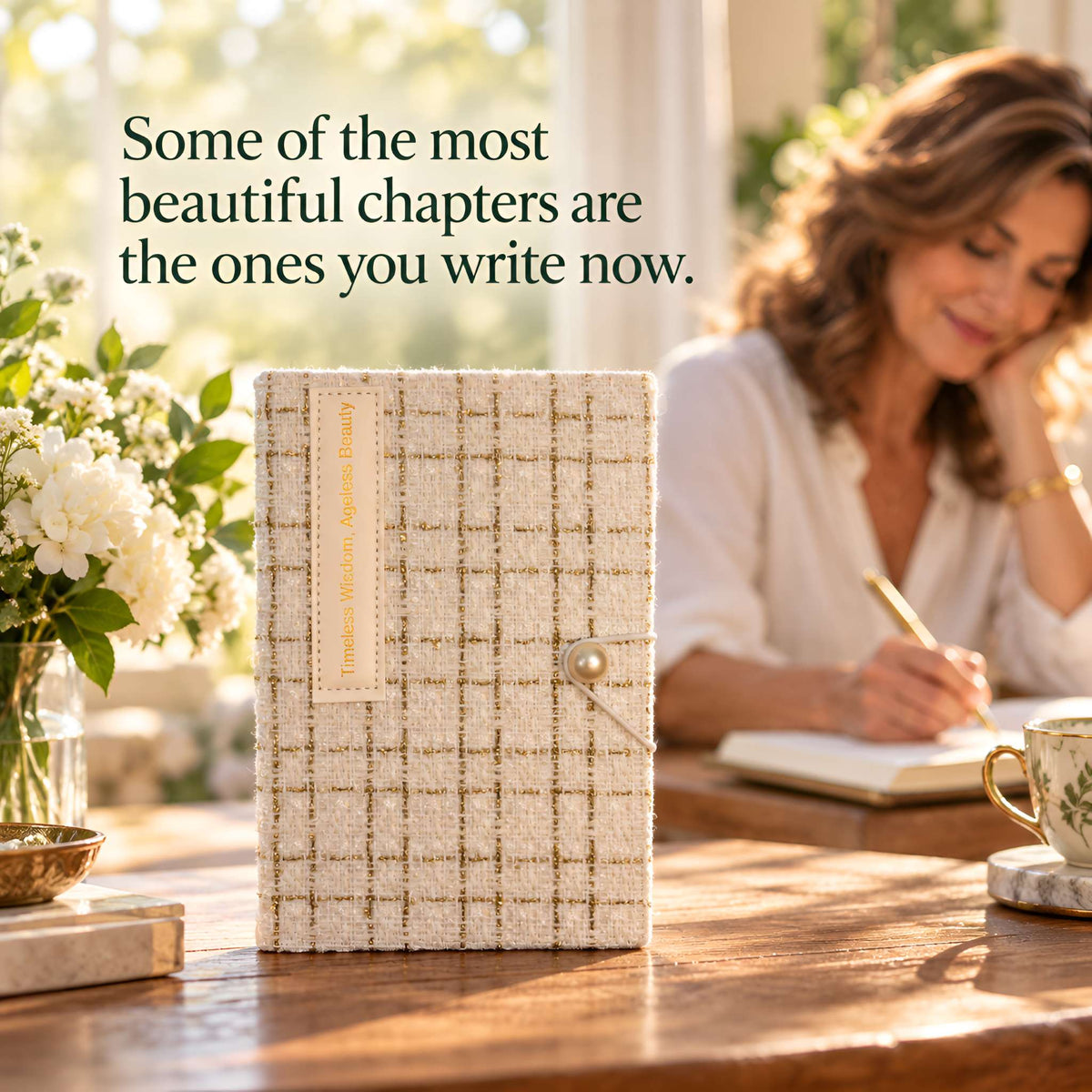 Ivory fabric journal beside a woman writing; text reads, “Some of the most beautiful chapters are the ones you write next.”