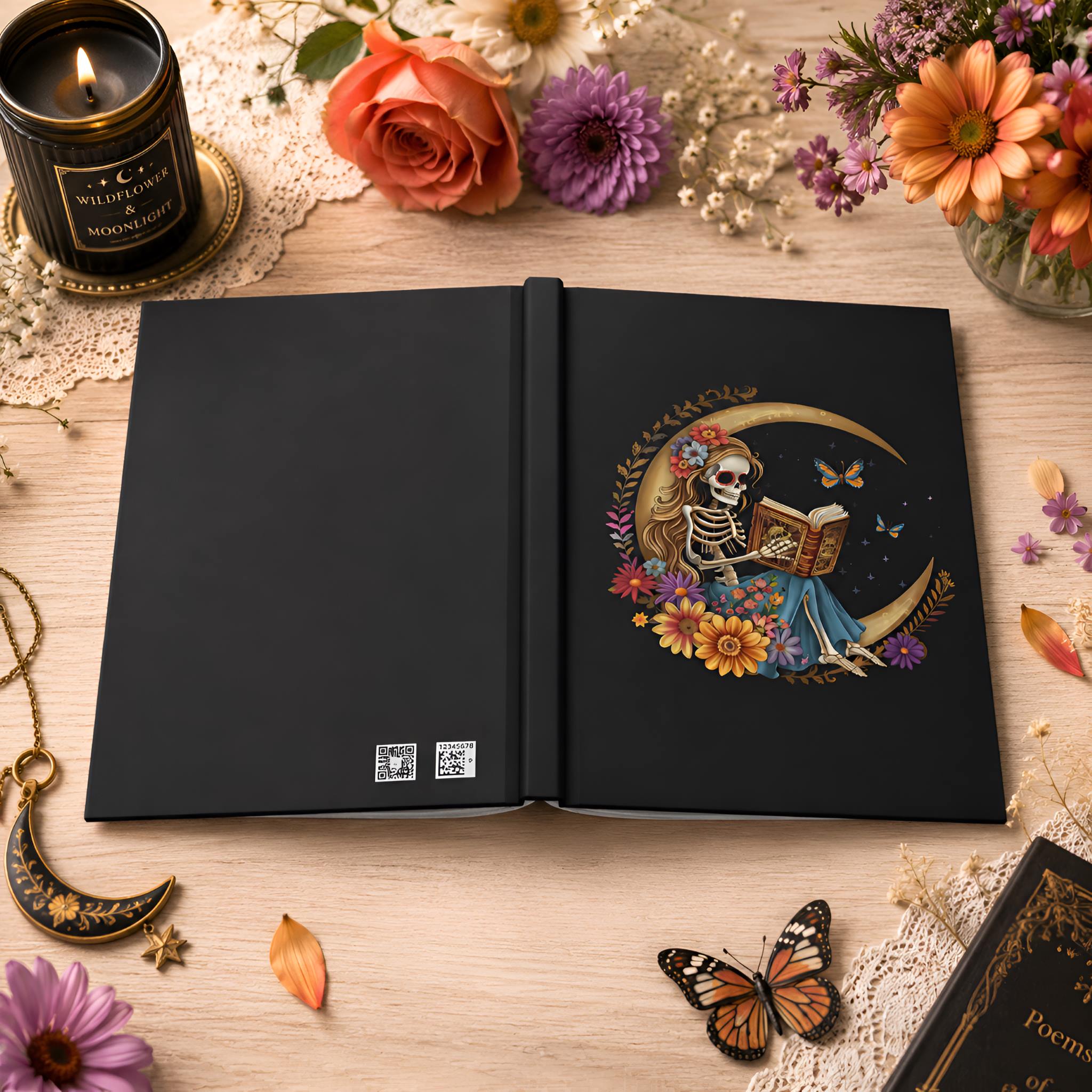 Gothic hardcover journal styled with black back cover, candle, flowers, and warm desk decor.