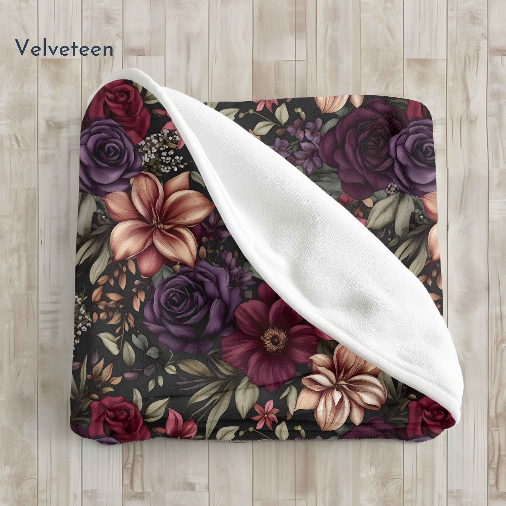 Floral patterned velveteen blanket with white border on wooden surface.