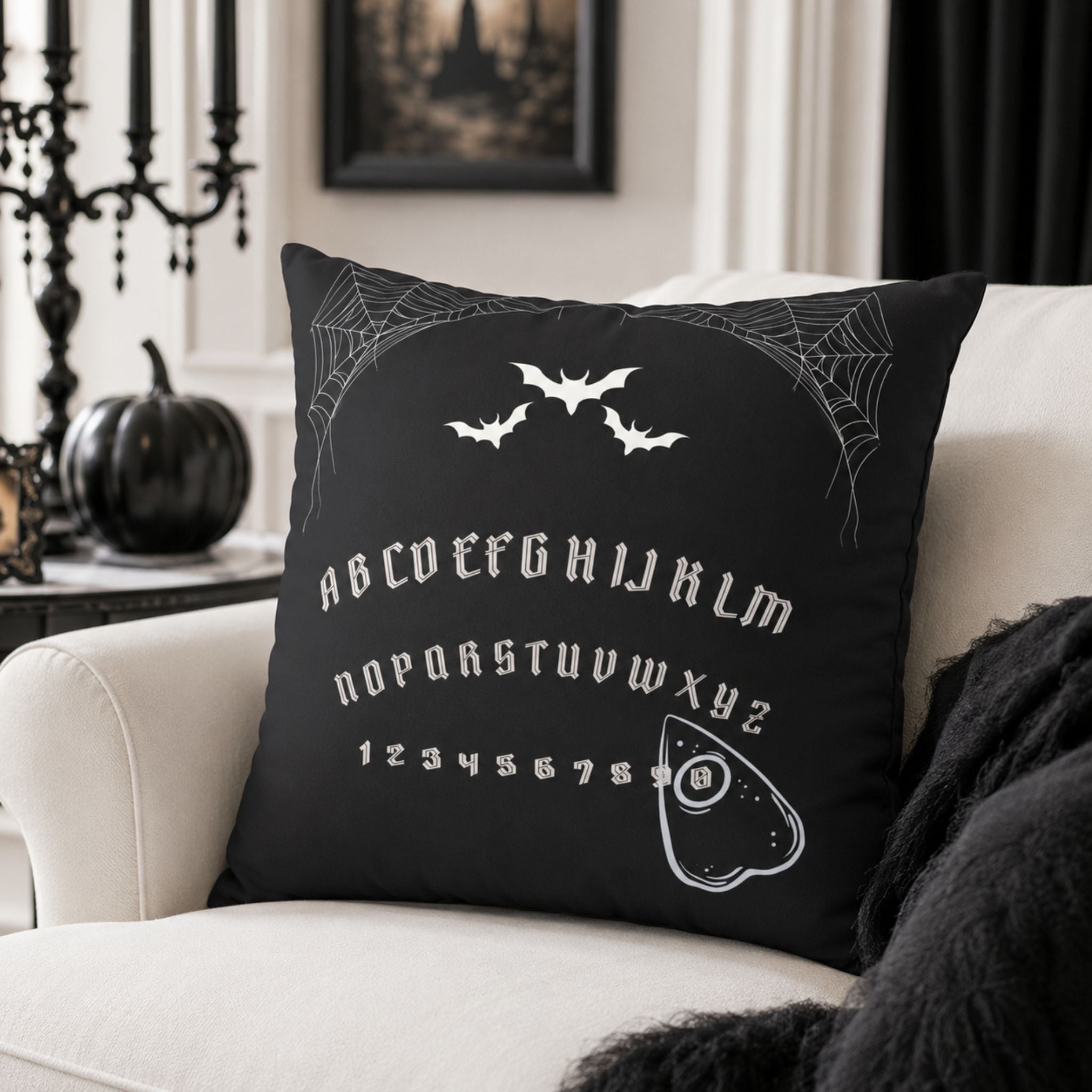 Spirit board pillow cover styled on white chair with black Halloween decor