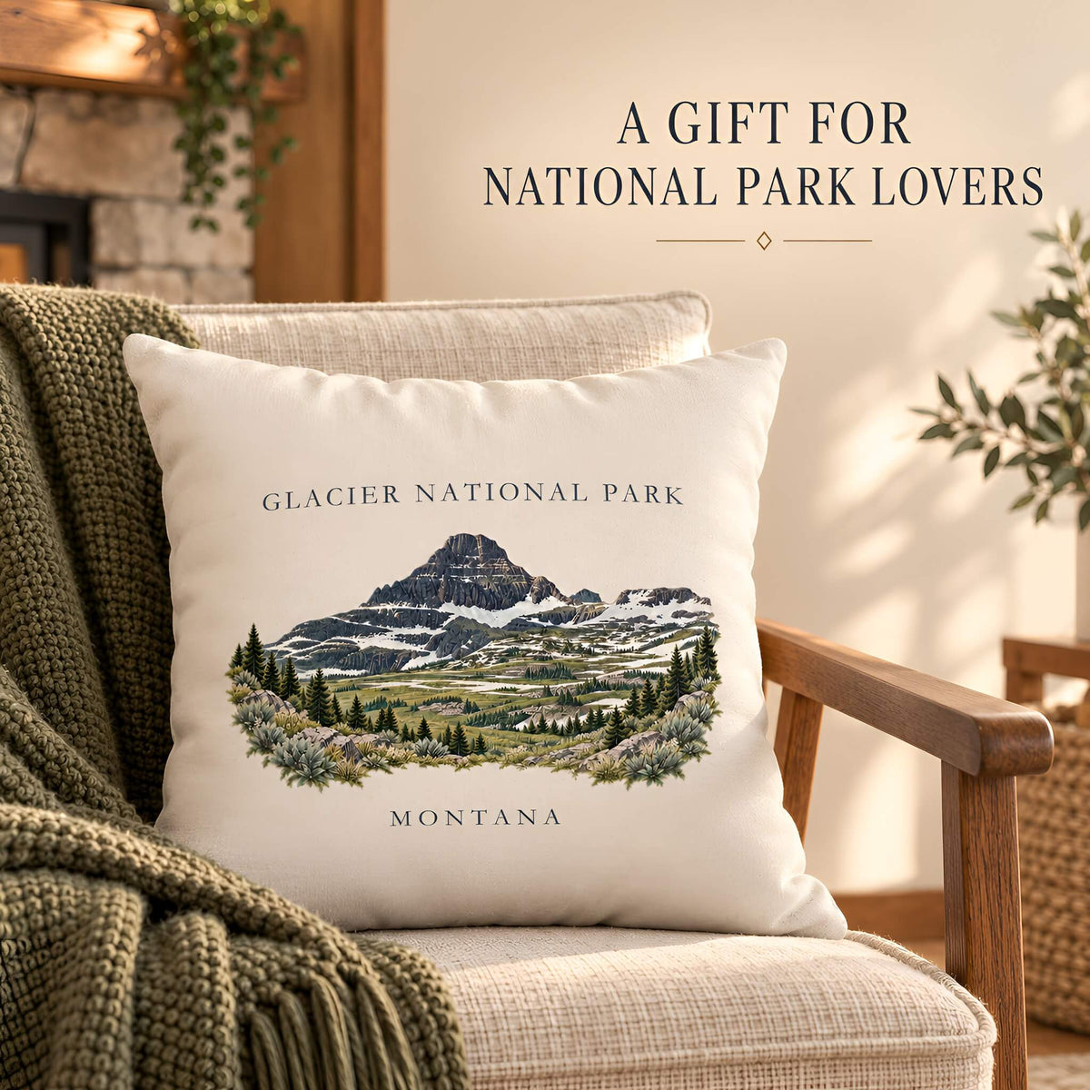 A square cream throw pillow cover featuring an illustrated Glacier National Park mountain scene with the text 'GLACIER NATIONAL PARK' and 'MONTANA', styled on a beige armchair with a green knit blanket. Text in the upper right reads 'A GIFT FOR NATIONAL PARK LOVERS'.