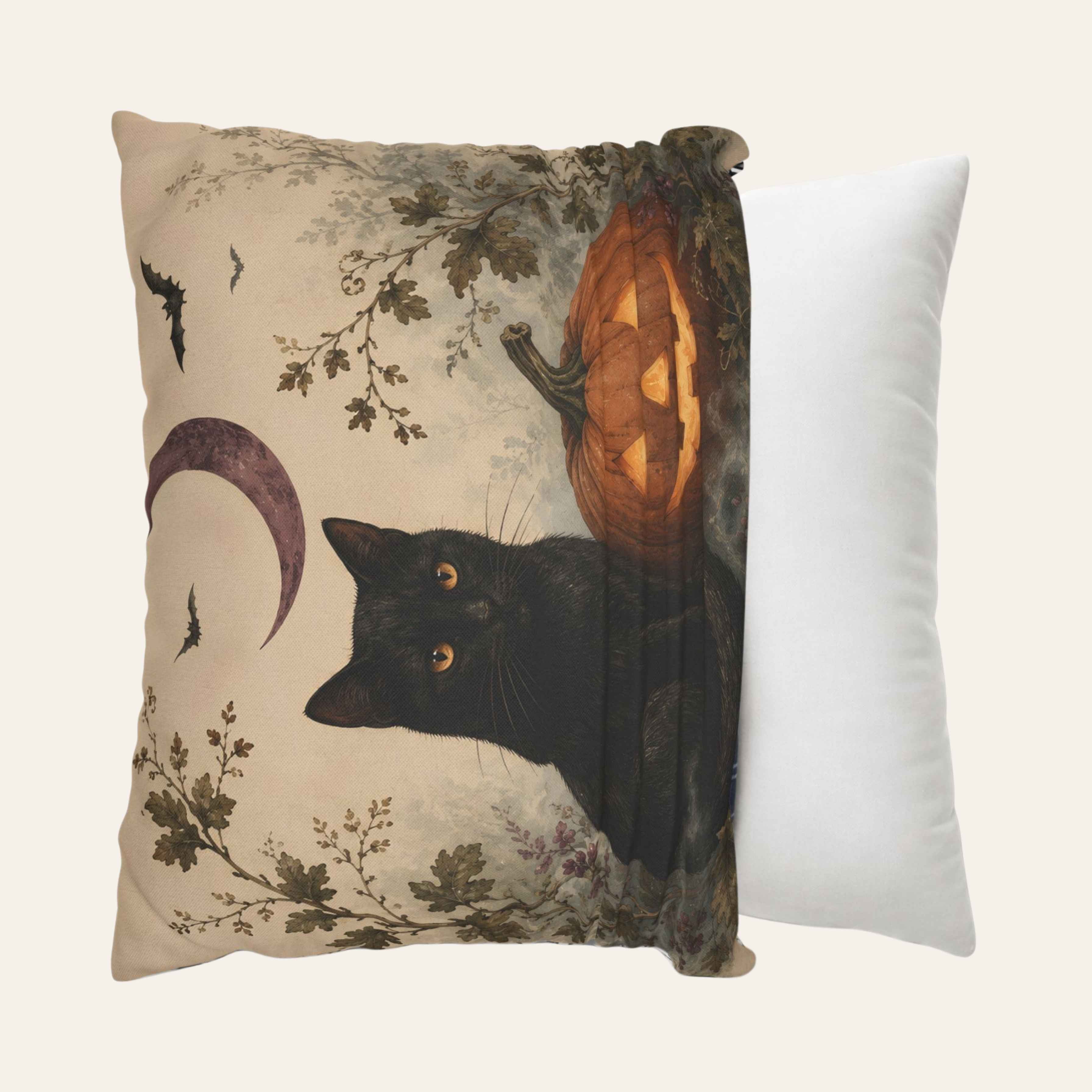 A square pillow cover with a Halloween-themed print featuring a black cat, a glowing jack-o'-lantern, bats, and a crescent moon on a beige background, shown next to a plain white pillow against a light cream backdrop.