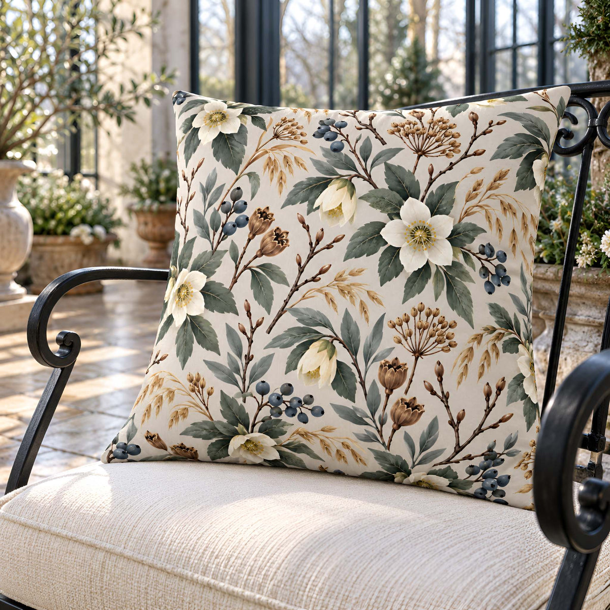 Winter floral botanical pillow with ivory flowers, blue berries and evergreen sprigs styled in a bright garden room
