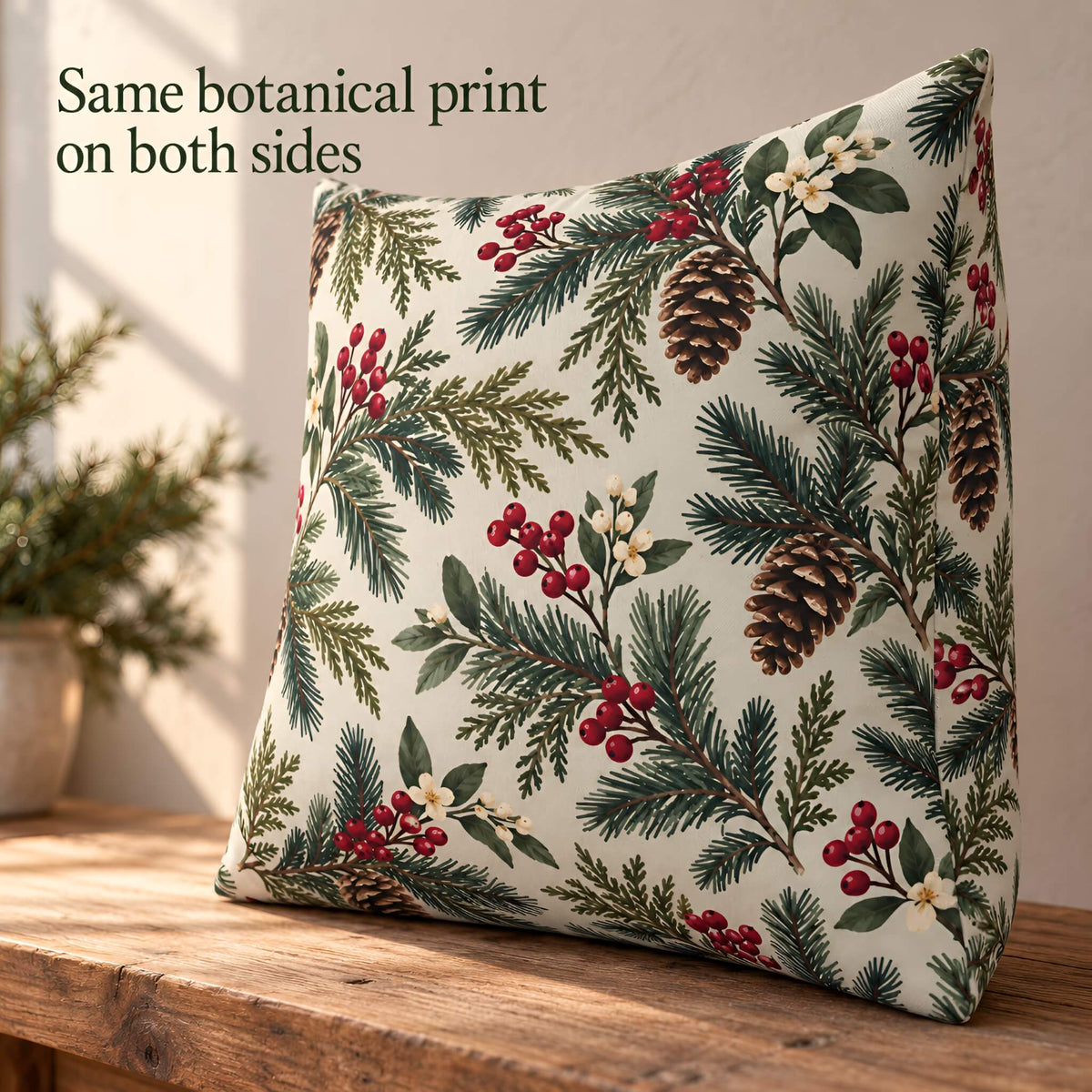 A square 20x20 pillow cover with a botanical pine and berry print, displayed on a wooden table with text overlay reading 'Same botanical print on both sides'.