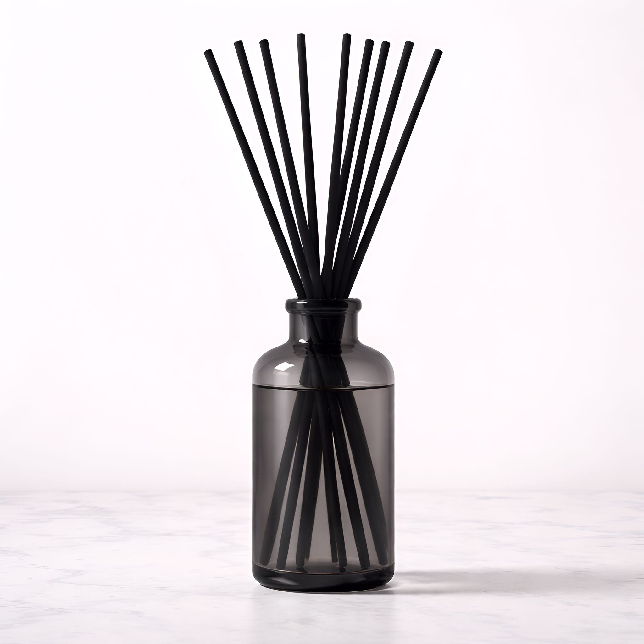 Black diffuser with sticks in a smoky clear bottle on a white background