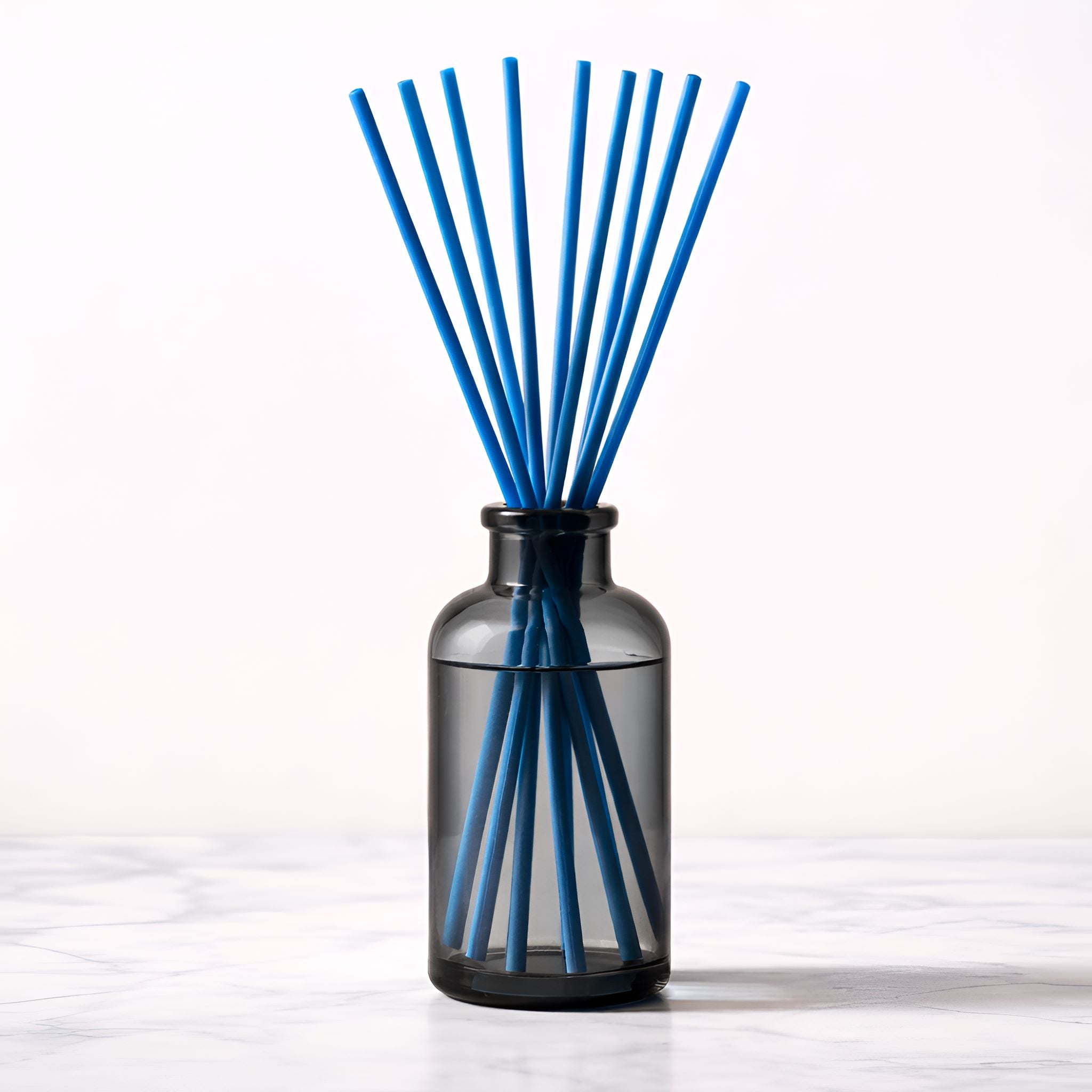 Black diffuser bottle with blue reed sticks on a white background