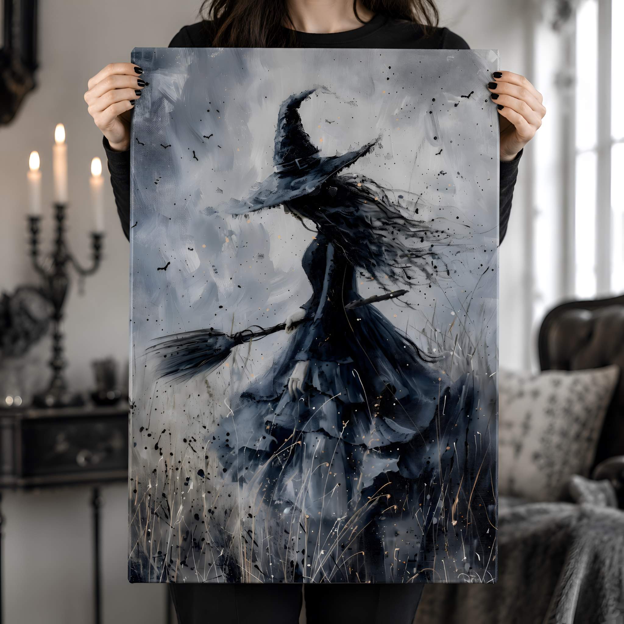 Person holding a whimsigoth painting of a witch with a broomstick in a room with candles and a couch.