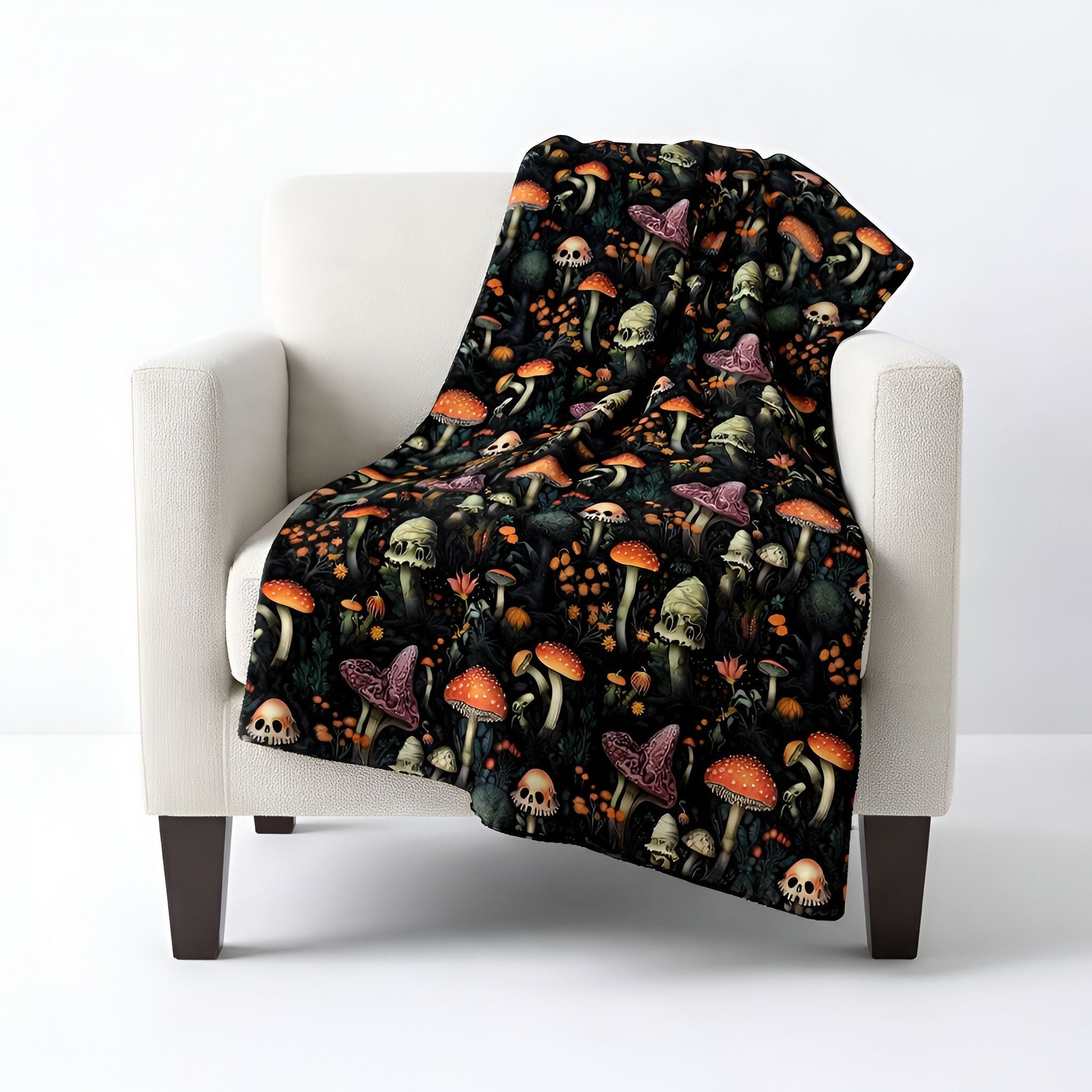 Whimsigoth throw blanket with a mushroom skull pattern draped over a white chair on a white background