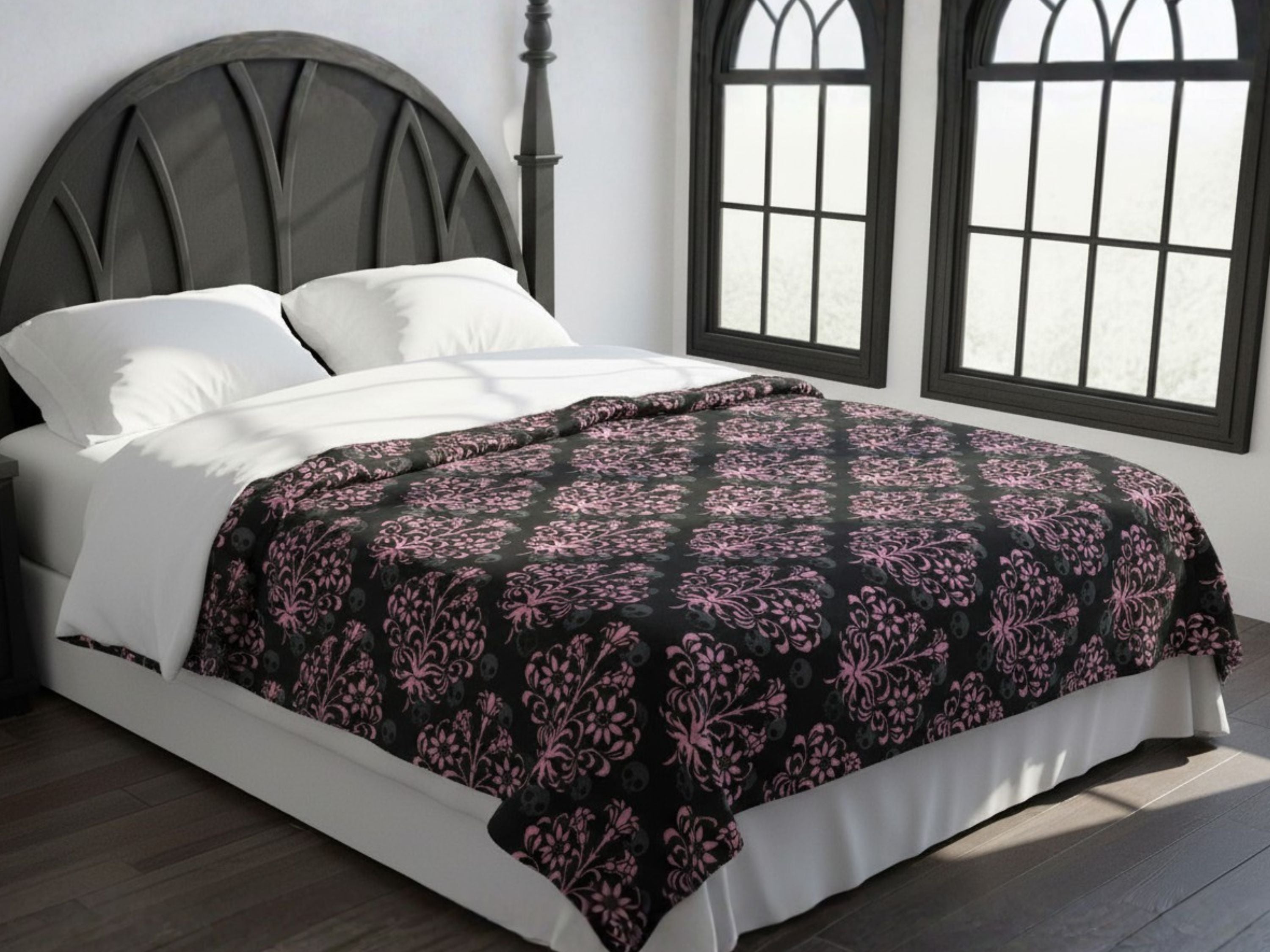 Bed with a Victorian gothic damask-patterned blanket in a room with large windows.