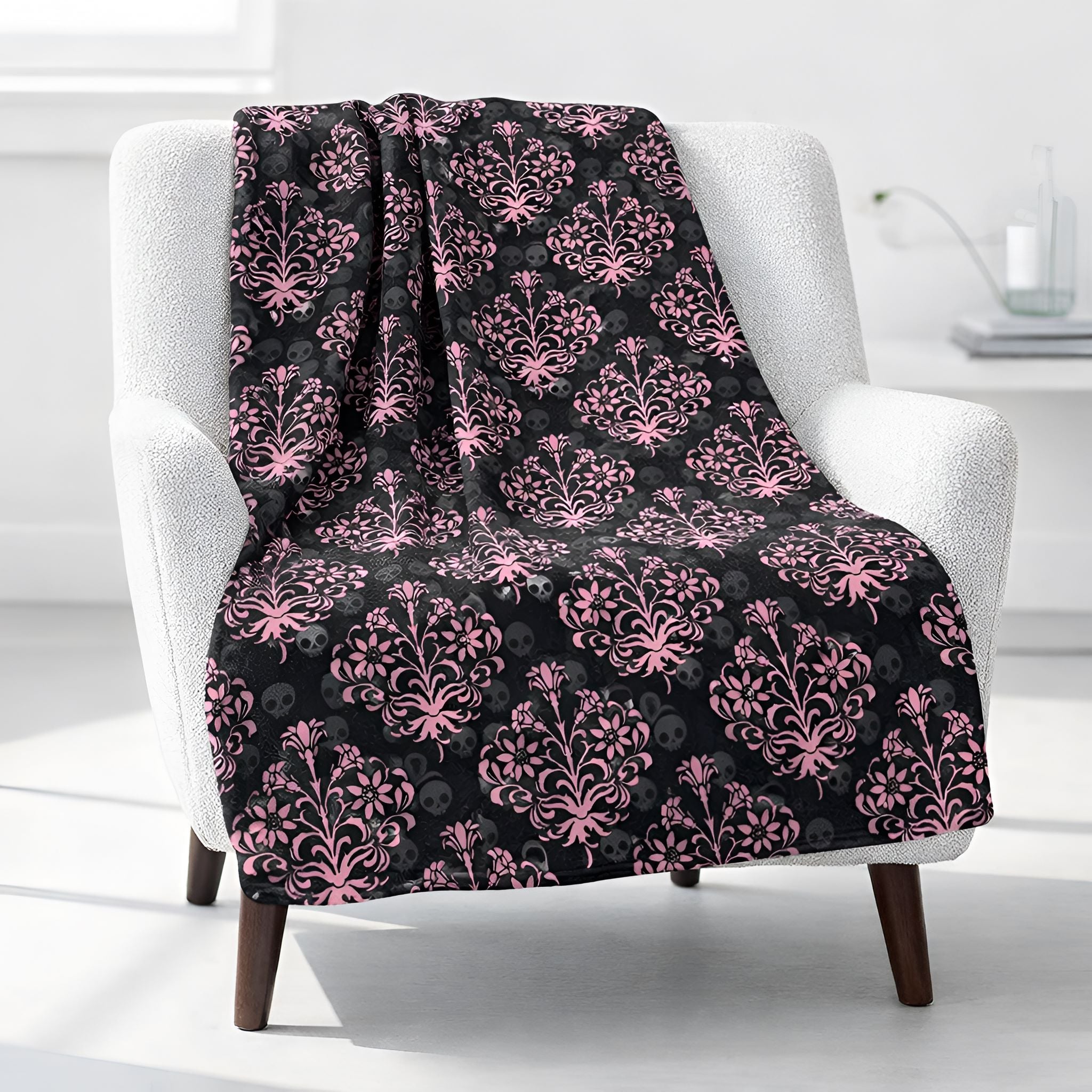 Victorian Gothic skull throw blanket draped over a white armchair in a minimalistic room.