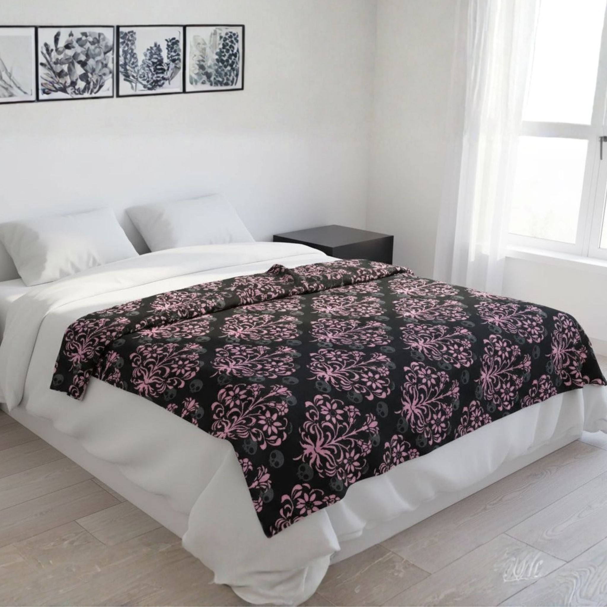 Bed with a gothic black and pink damask patterned blanket in a bright bedroom.