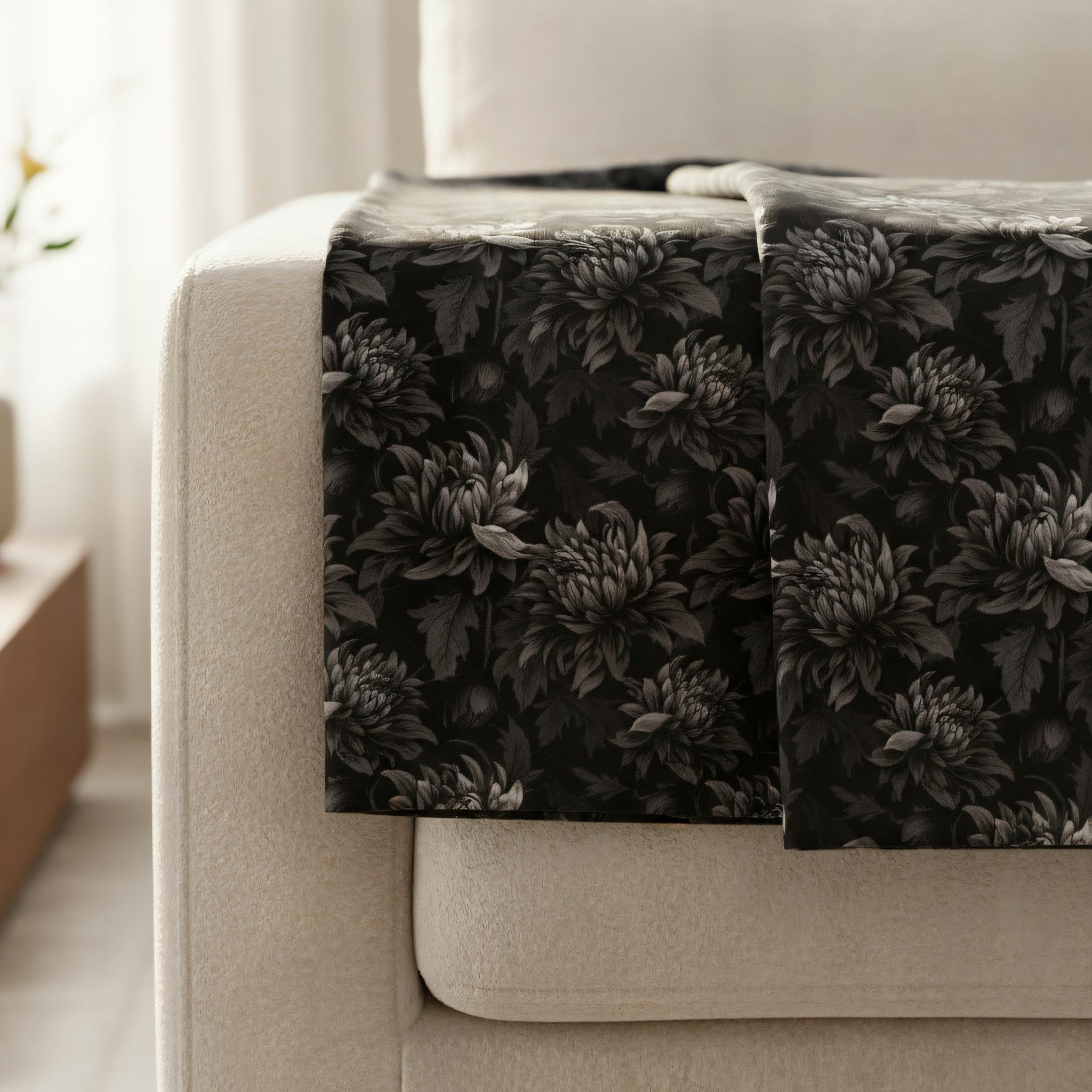 Black and gray floral throw blanket draped over a sofa in a living room setting.