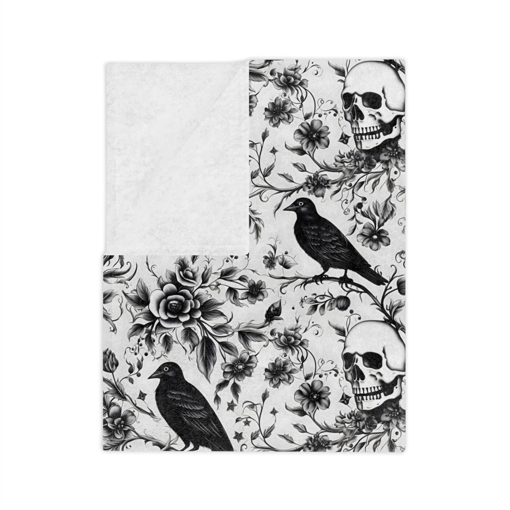 Black and white gothic velveteen throw blanket with skull, raven, and floral pattern with white backing.