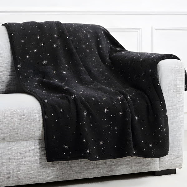 Black celestial throw blanket draped over a couch in a modern room.