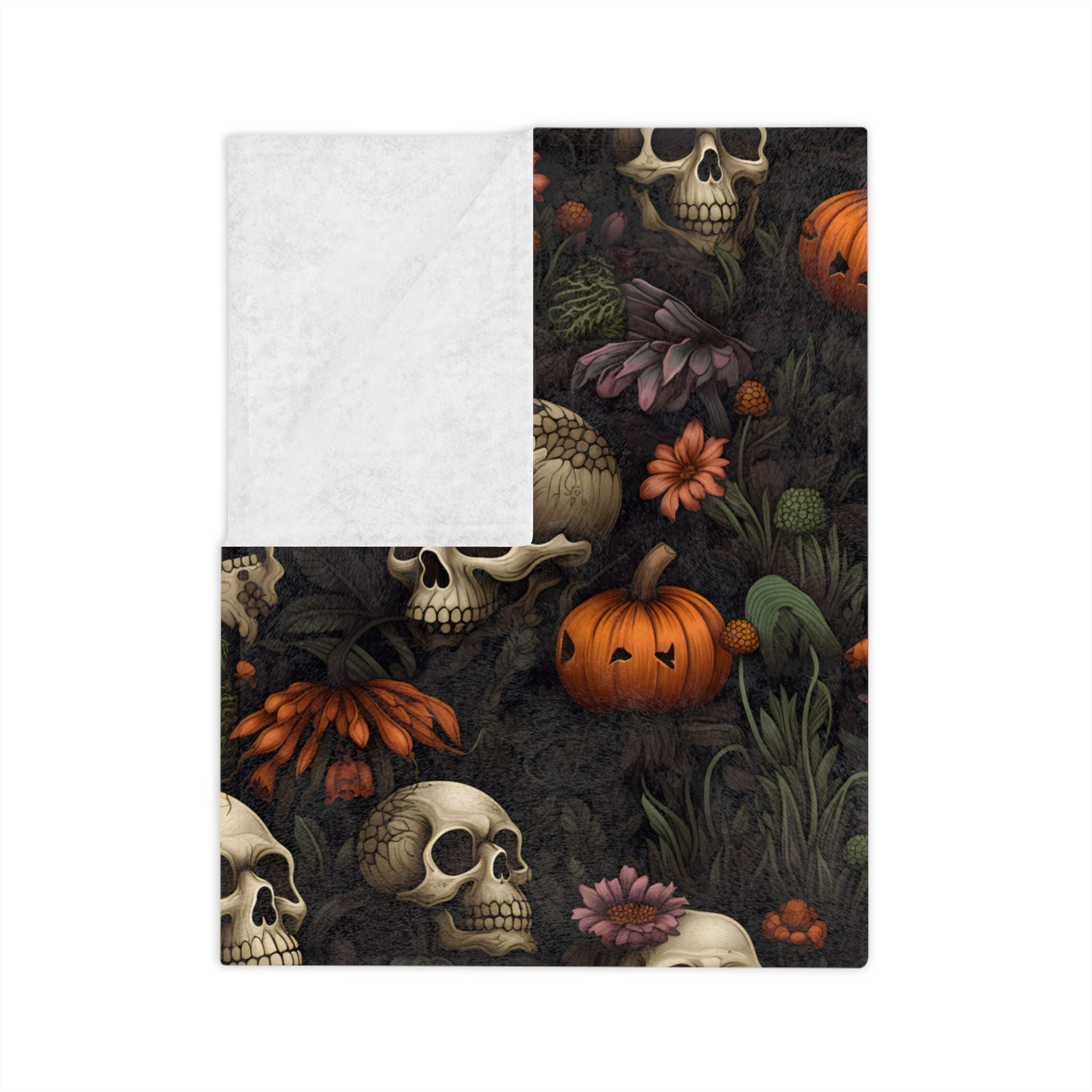 Folded dark floral skull throw blanket with pumpkins on a black background with white backside.