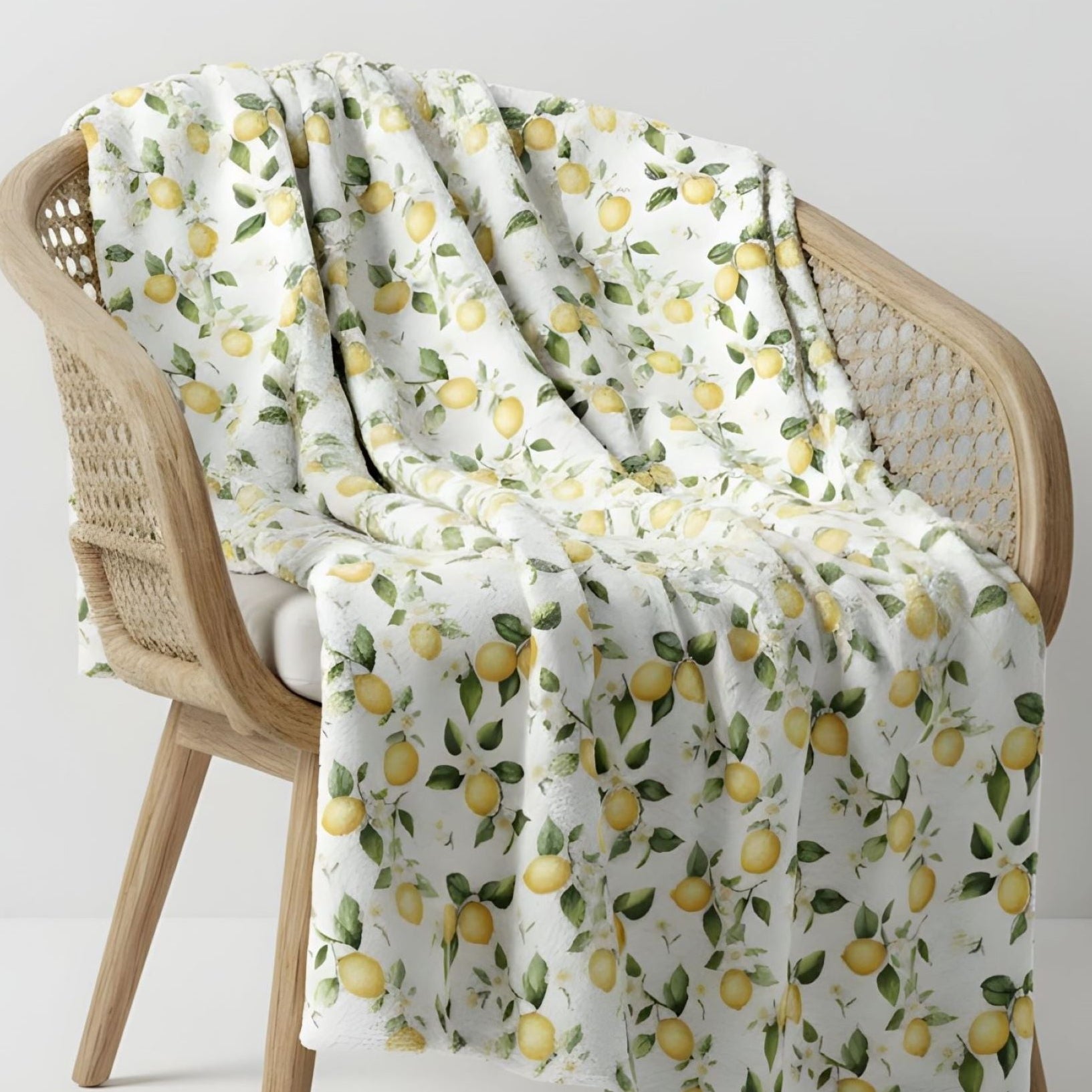 A lemon-patterned throw blanket on a wicker chair for a beautiful summer aesthetic. 