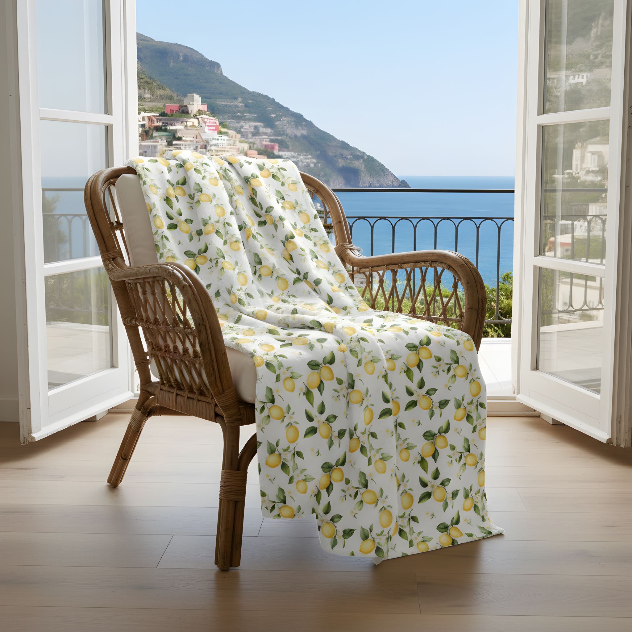 Wicker chair with a lemon throw blanket on a balcony with a view of the Amalfi Coast.