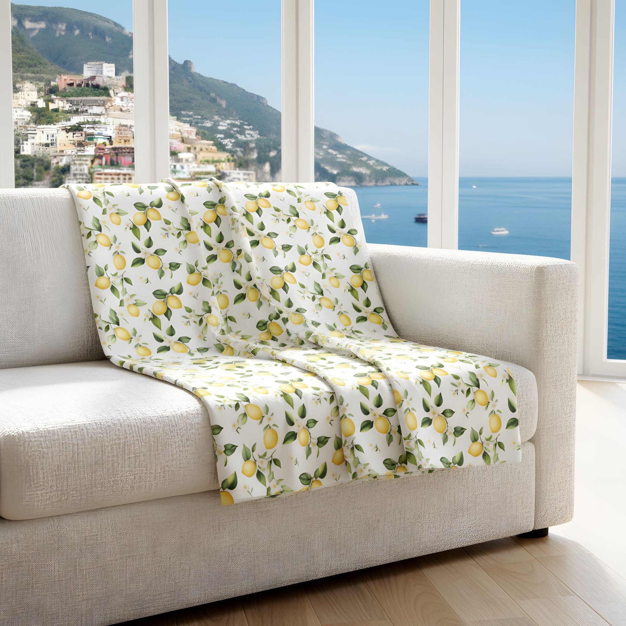 Beige sofa with a lemon throw blanket in a room with large windows overlooking the Amalfi Coast.