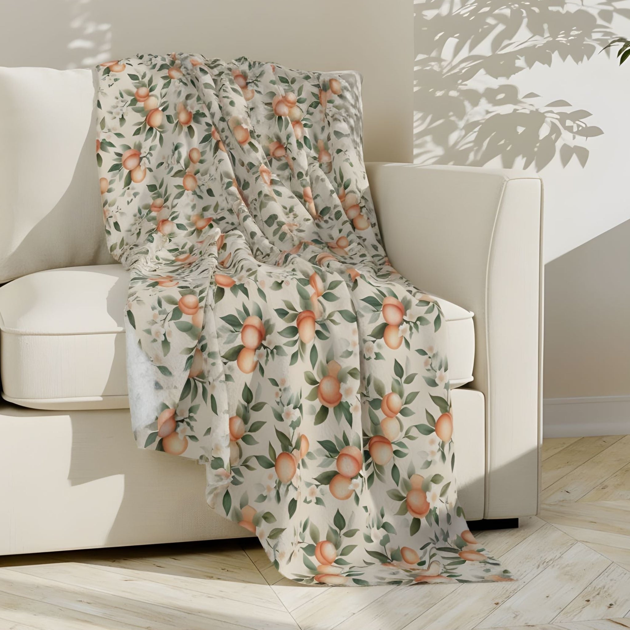 A fruit-styled peach-patterned throw blanket draped over a white sofa in a bright room.