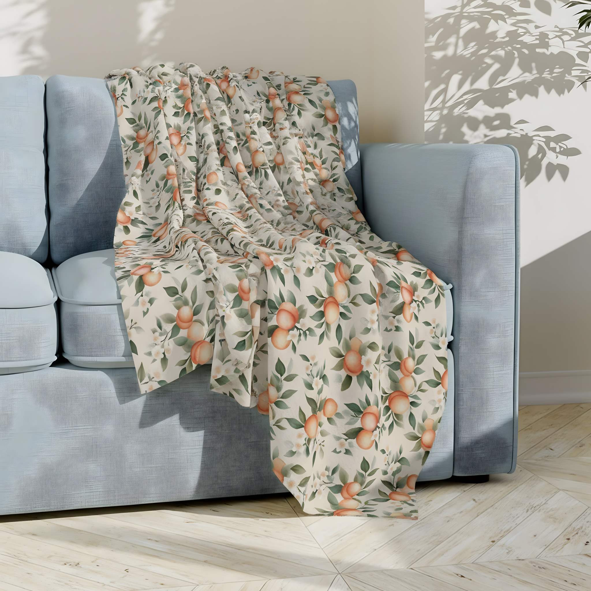 Peach-patterned throw blanket draped over a blue sofa in a cottagecore styled room.