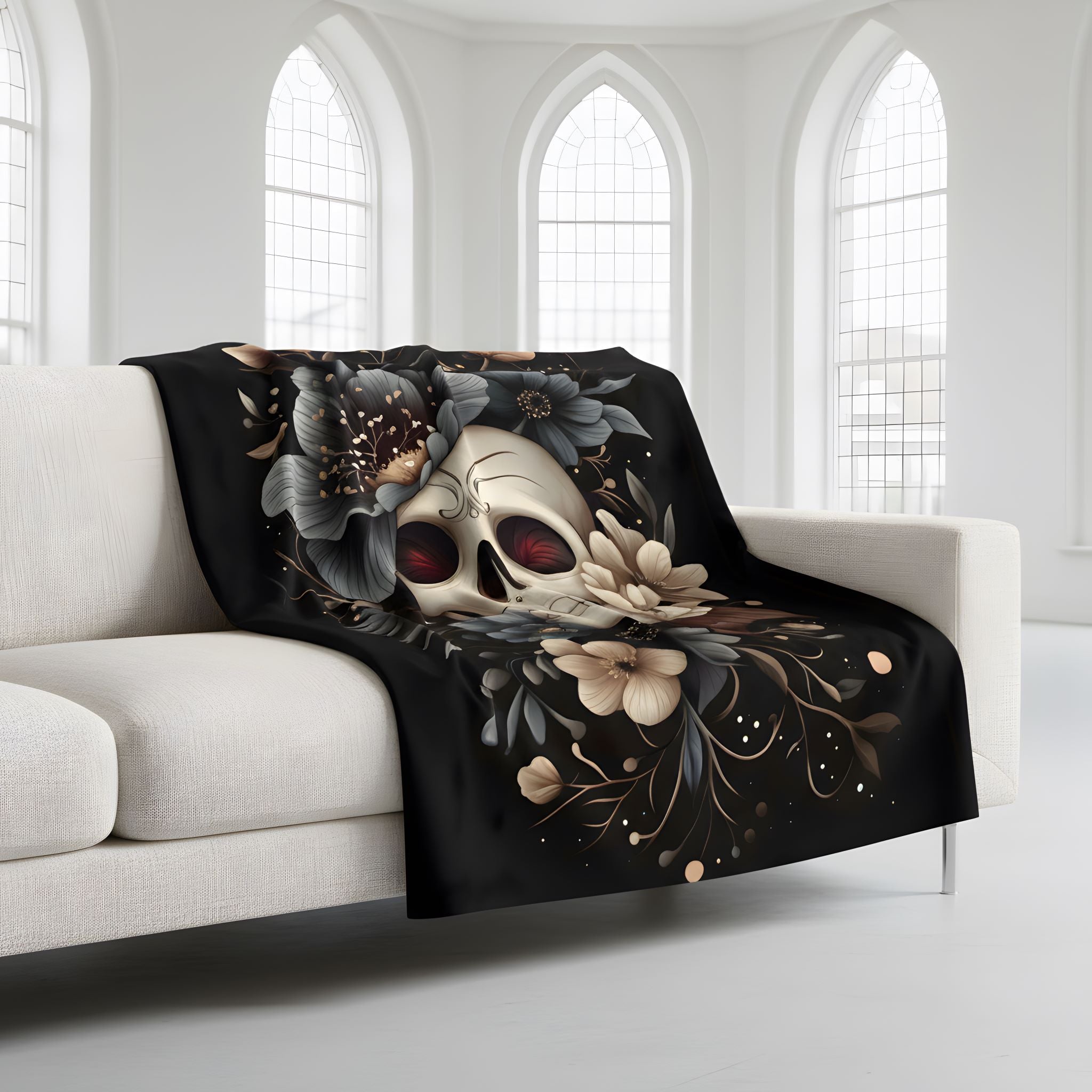 Gothic throw blanket draped on sofa with skull, muted flowers, and black background in smooth velveteen fabric.