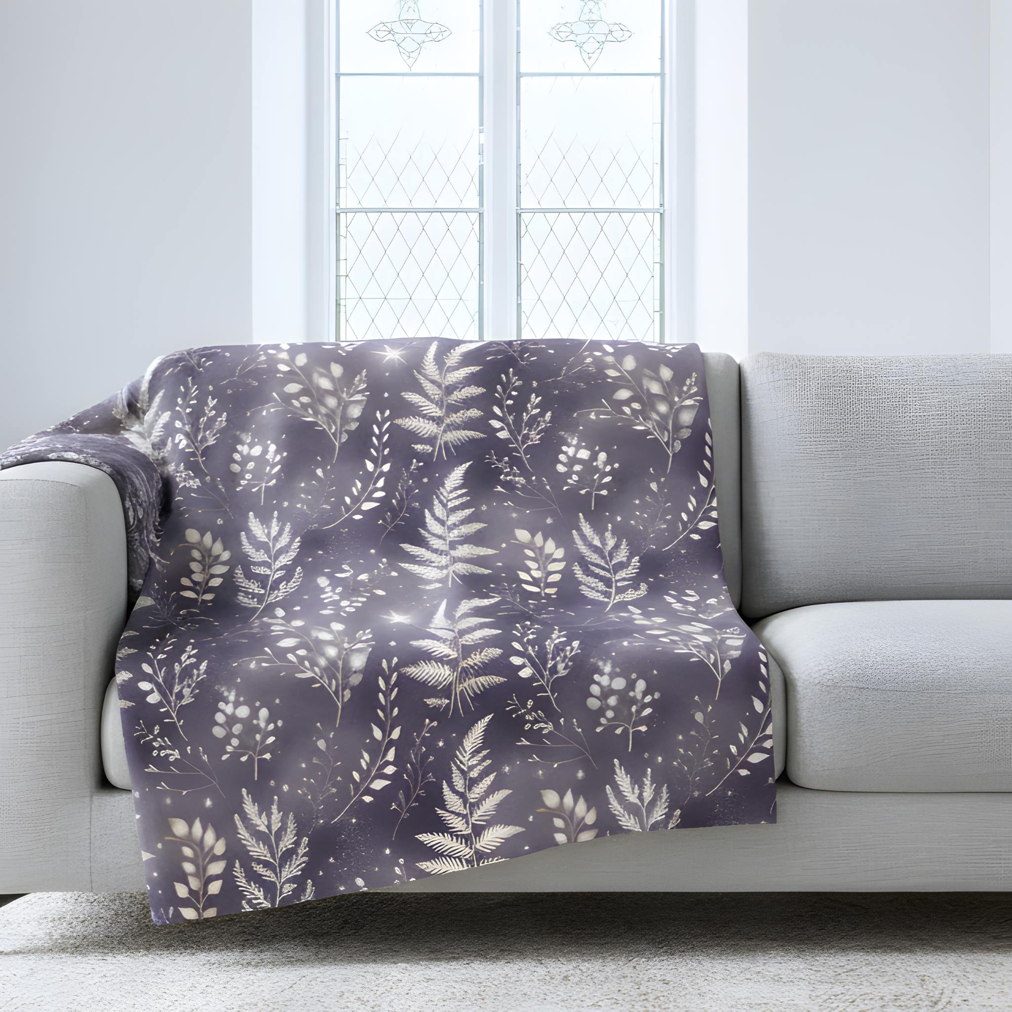 Whimsigoth velveteen throw blanket with moonlit fern print draped over a light sofa.