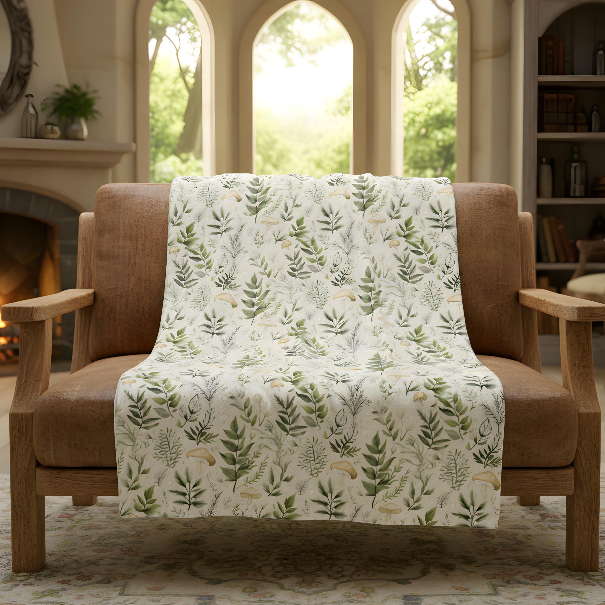 Mushroom and botanical throw blanket styled over a chair in a warm enchanted cottage room.