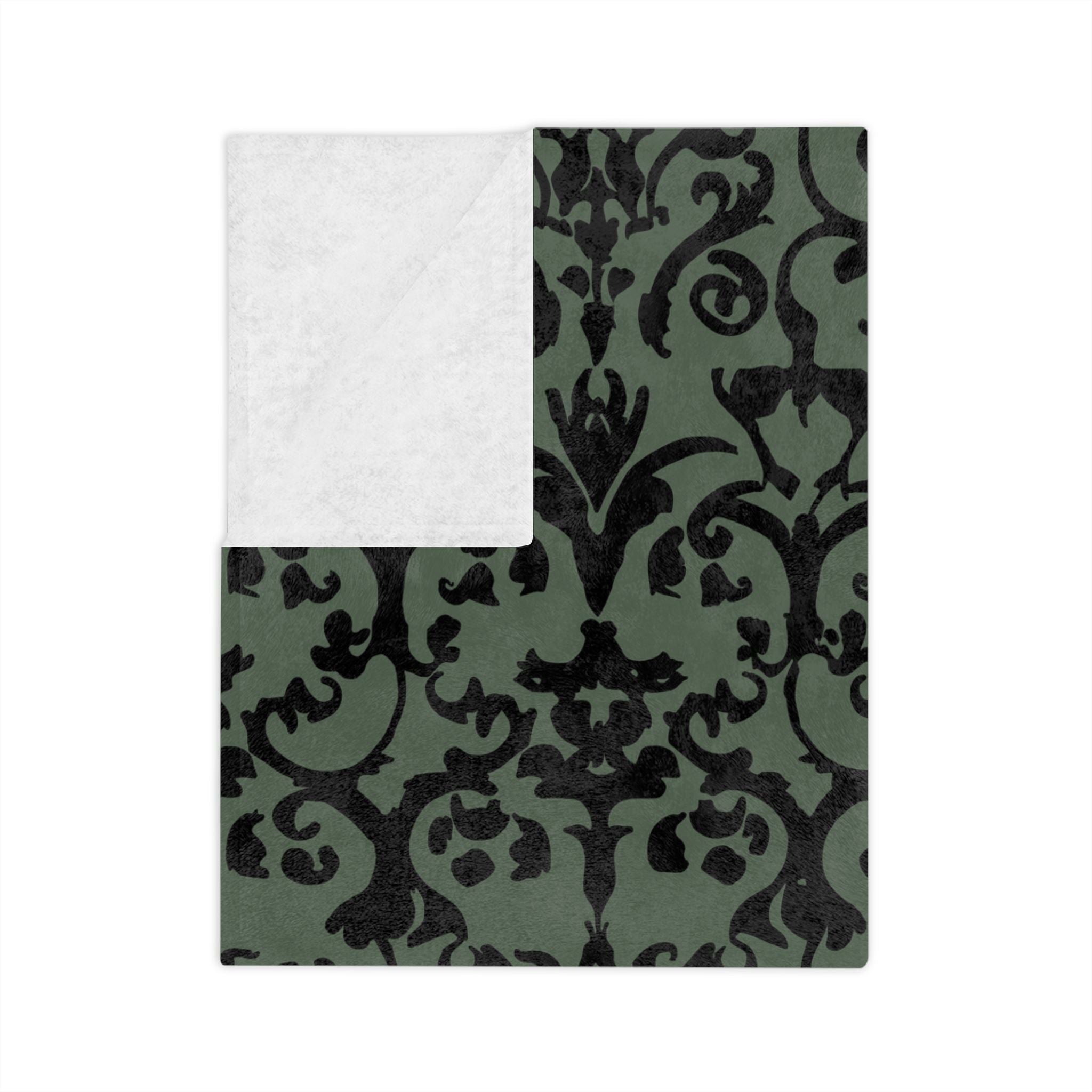 Folded Victorian Gothic throw blanket with black damask design on a dark green background with white underside.