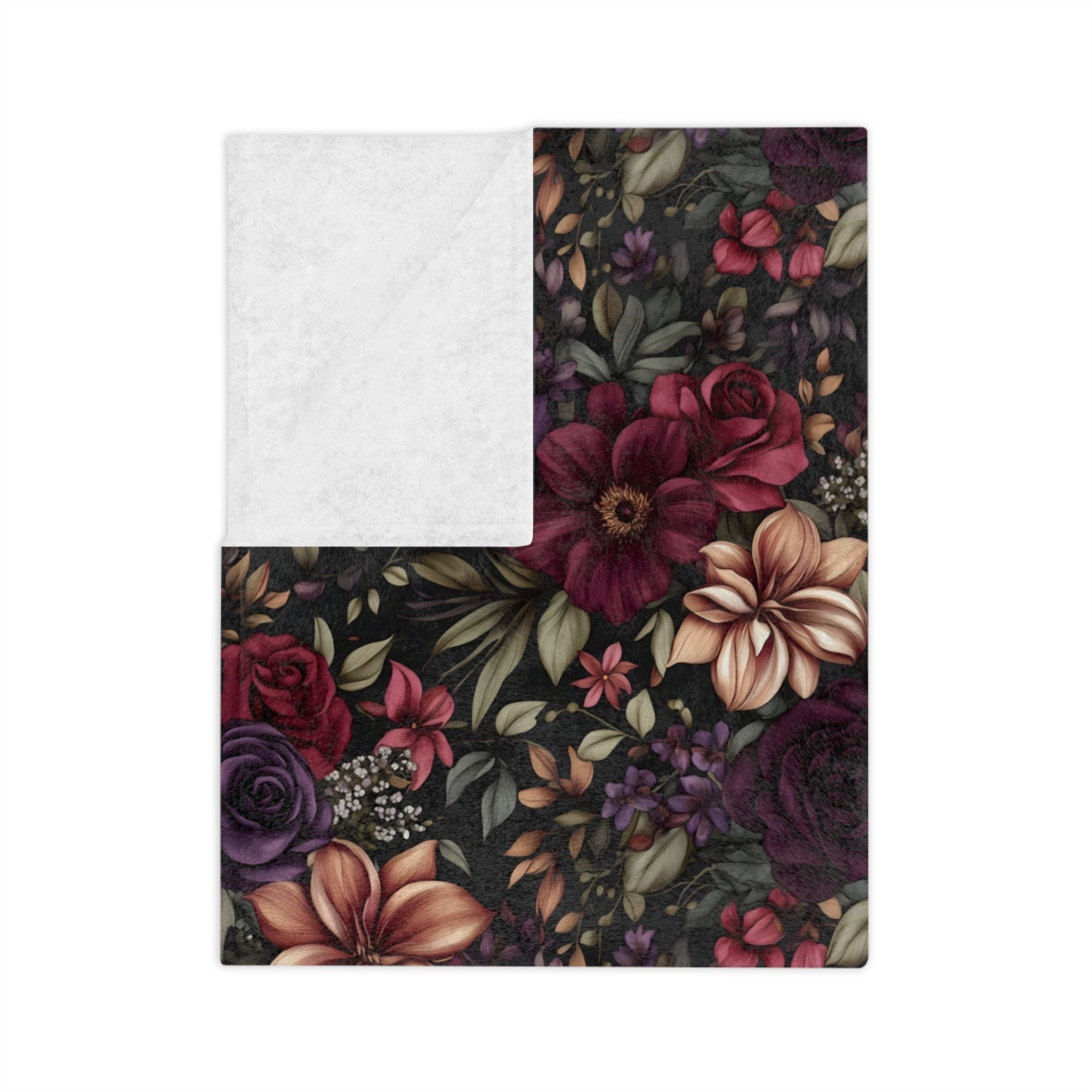 Folded black floral throw blanket with plum, burgundy, blush, and olive botanical print with white backside.