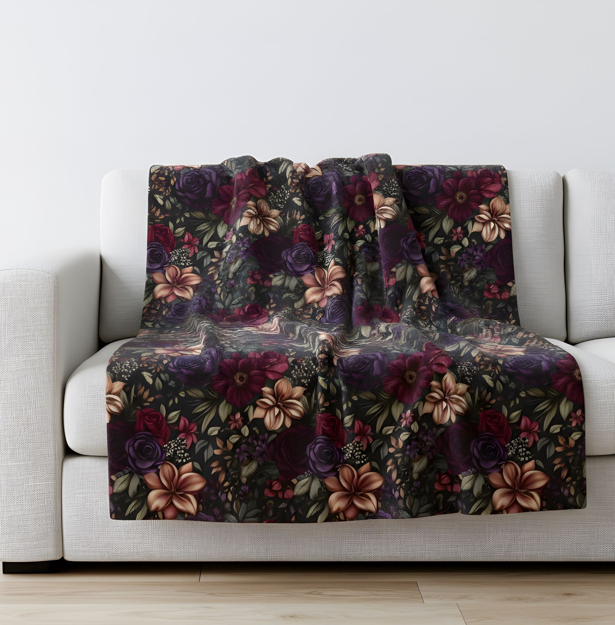 Dark floral velveteen throw blanket draped over a white sofa in a bright room.
