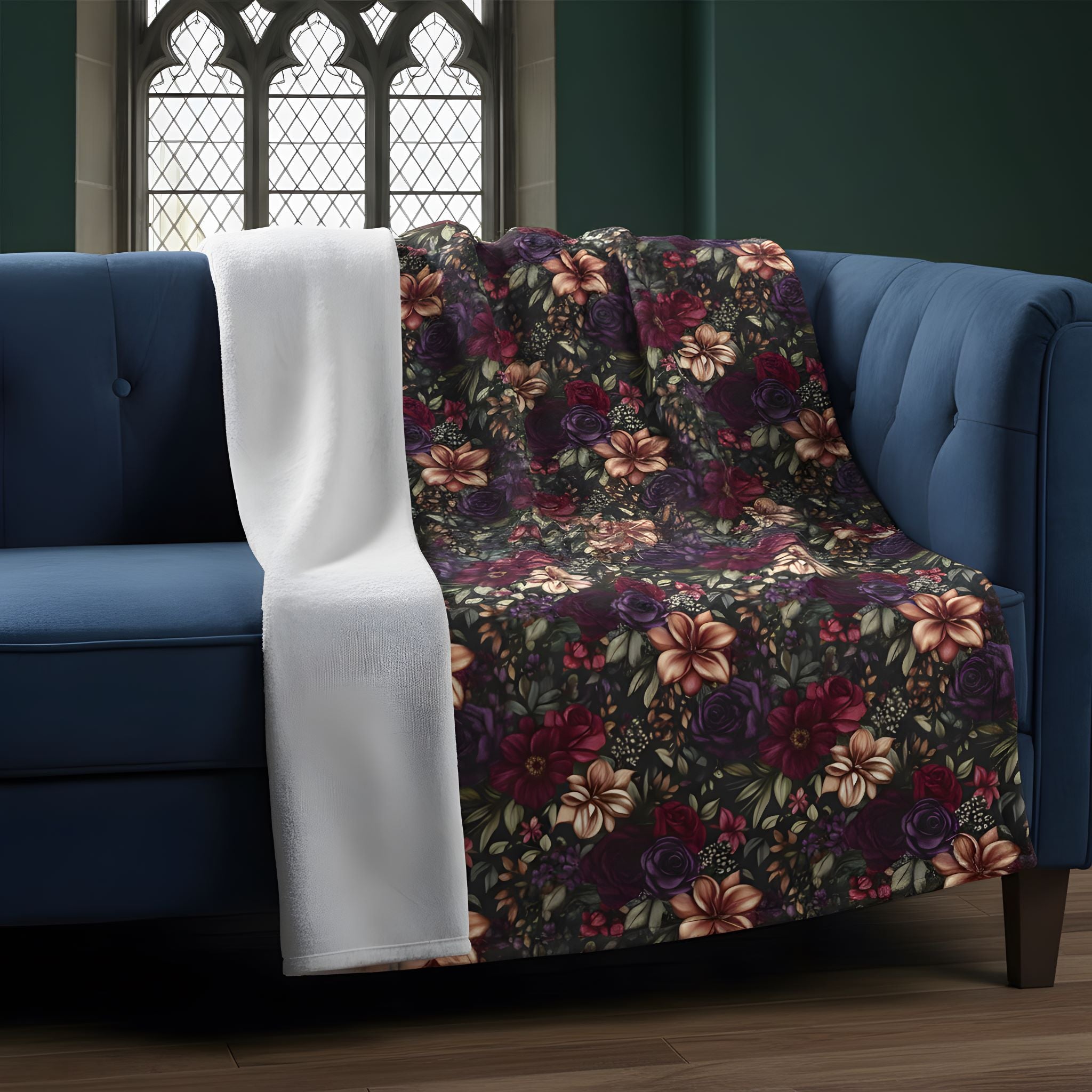 Burgundy and plum floral sherpa blanket folded over a blue sofa with moody Gothic decor.