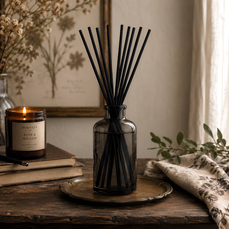 Diffuser reeds collection with black reed diffuser, candle, botanical art, greenery, and warm cottage-gothic styling.