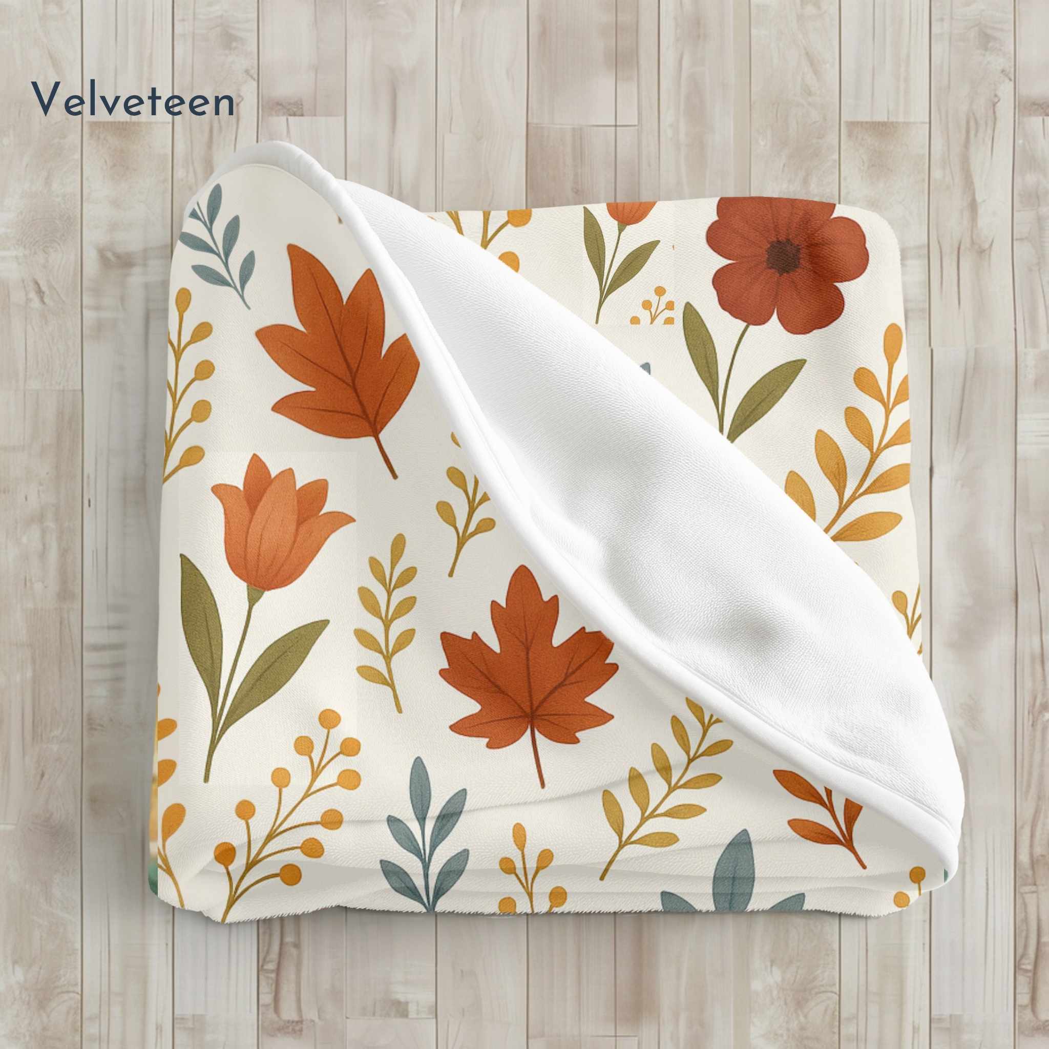 Floral patterned velveteen blanket with orange flowers and green leaves on a wooden surface.