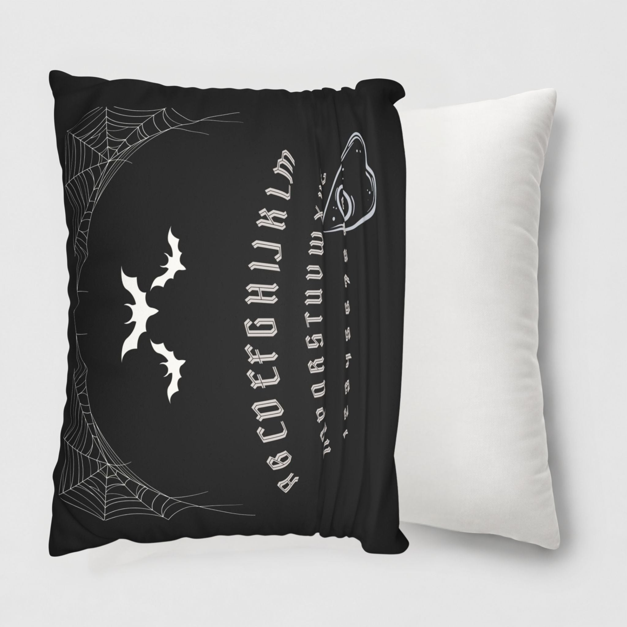 Black ouija board pillow with white spider web and bat design on a white background
