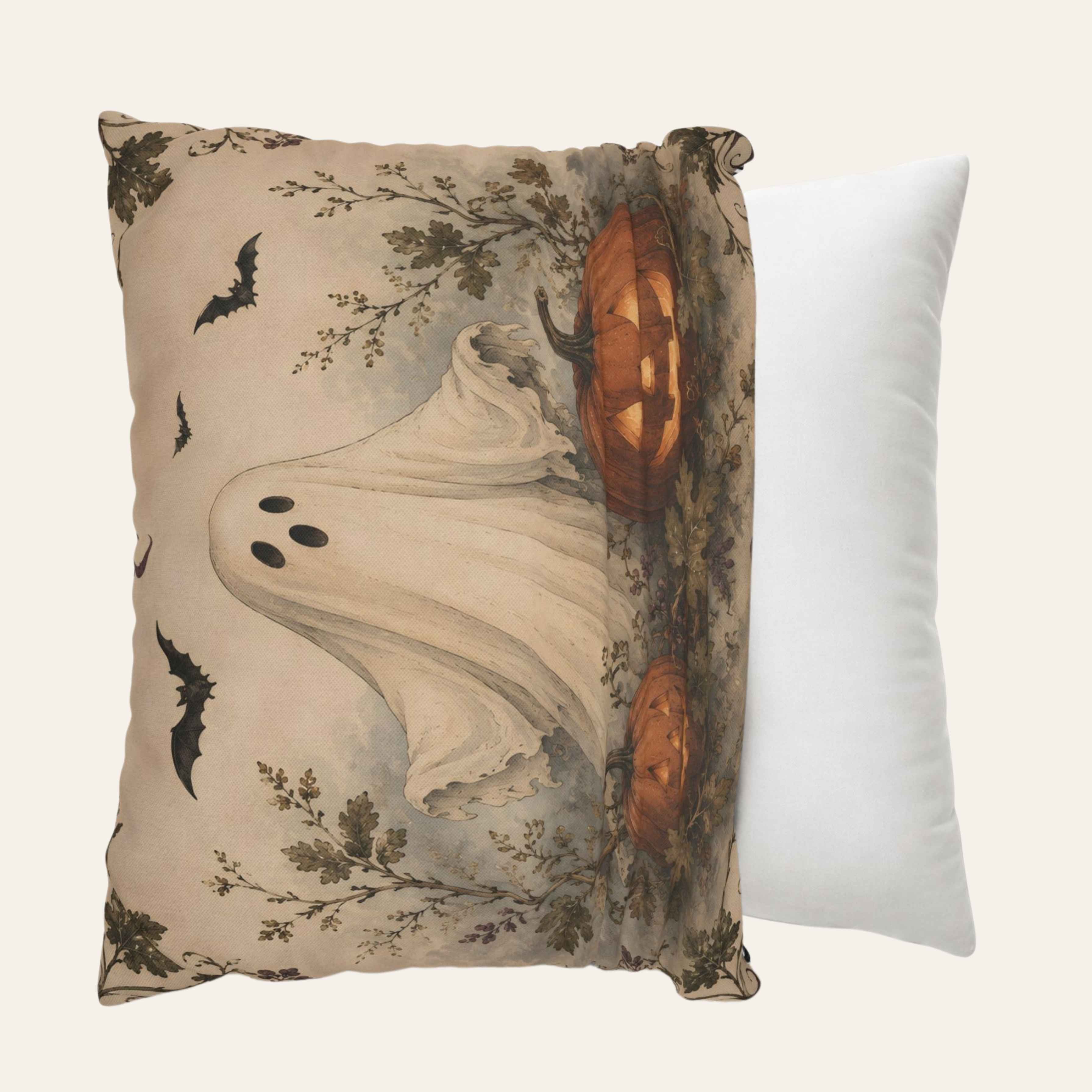 A decorative throw pillow cover featuring a vintage-style Halloween print with a ghost, bats, pumpkins, and foliage on a beige background, shown next to a plain white pillow against a light cream backdrop.